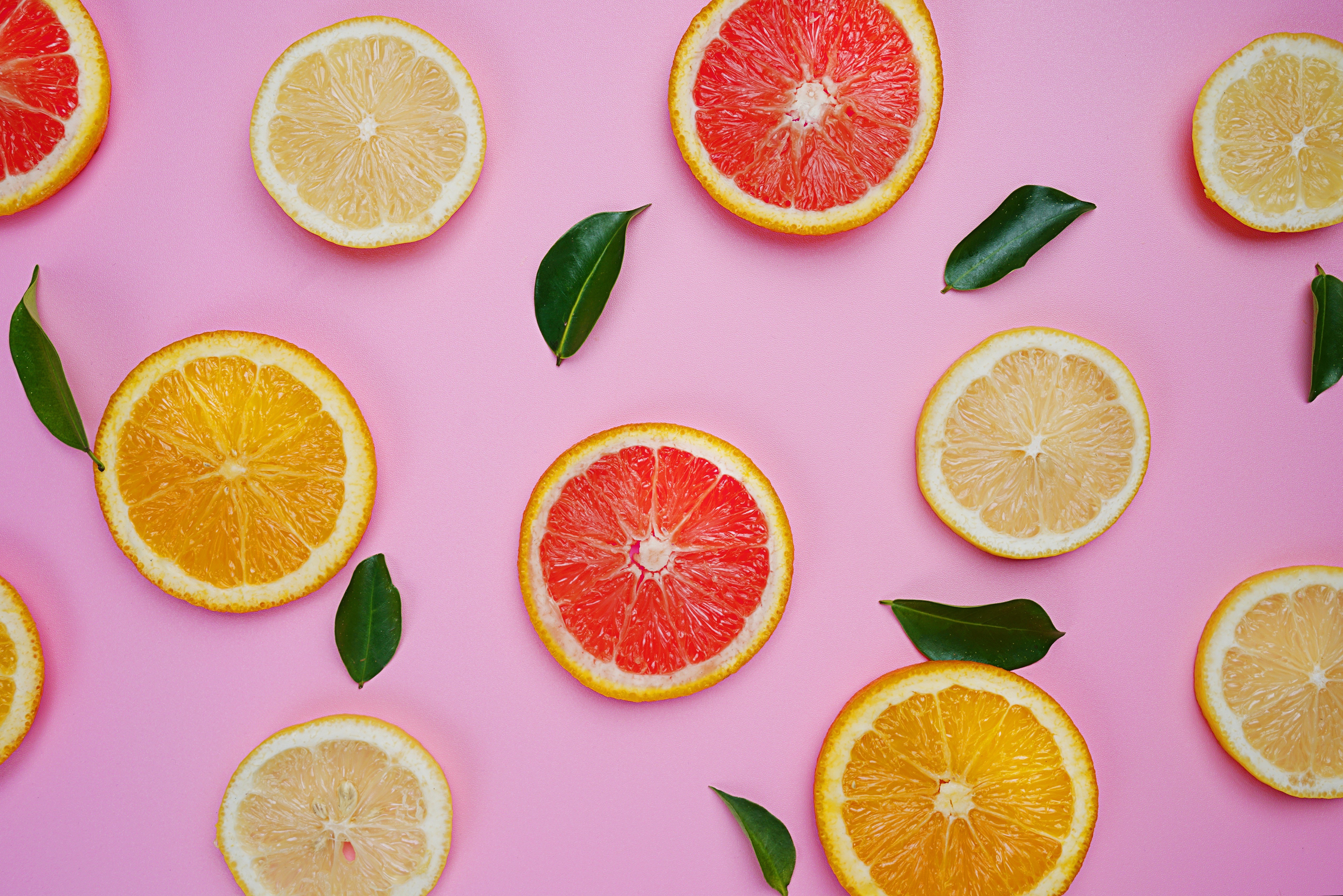 Citrus slices and leaves on pink background HD Wallpaper