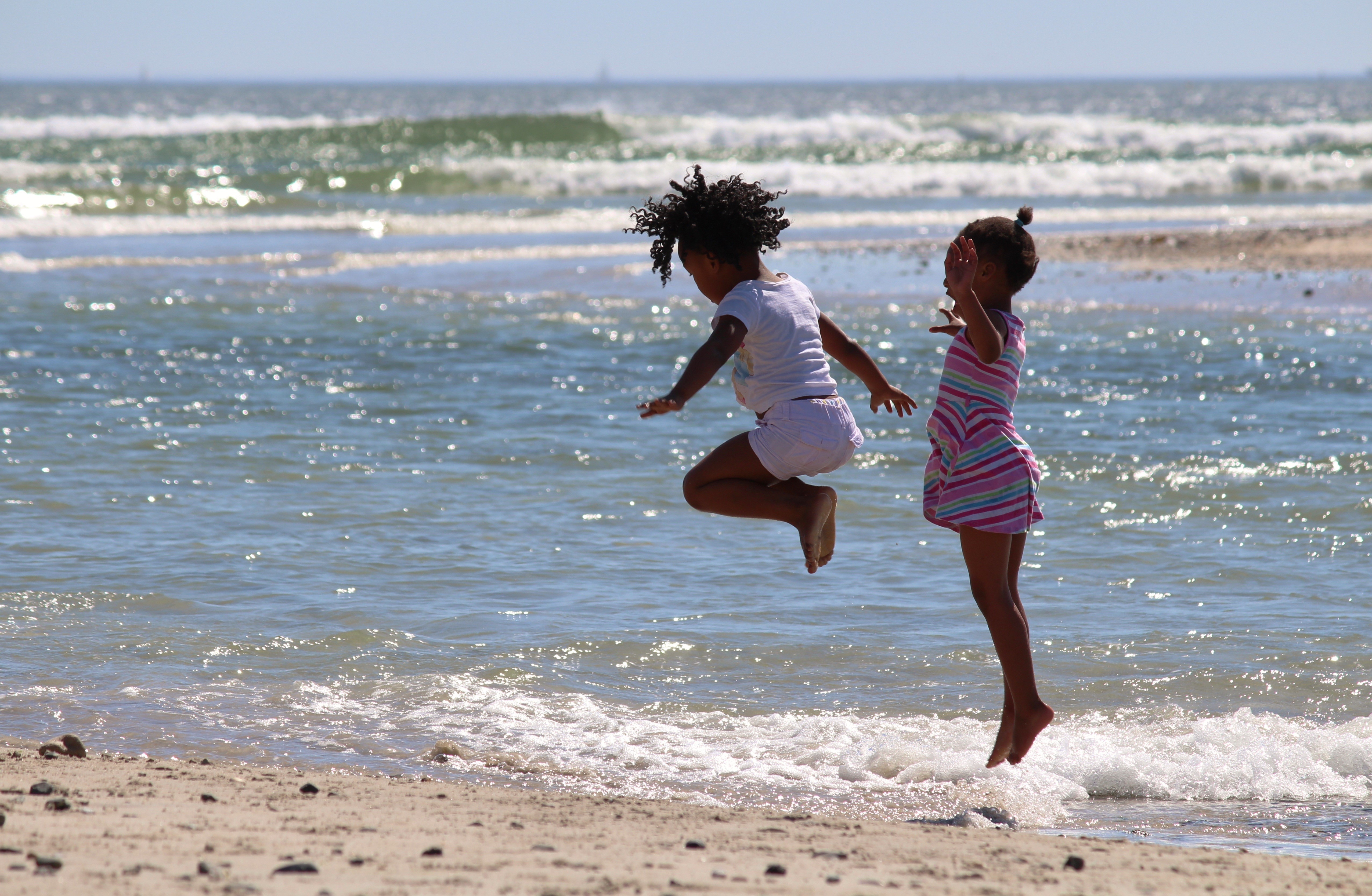 Two little girls jumping in the sea HD Wallpaper