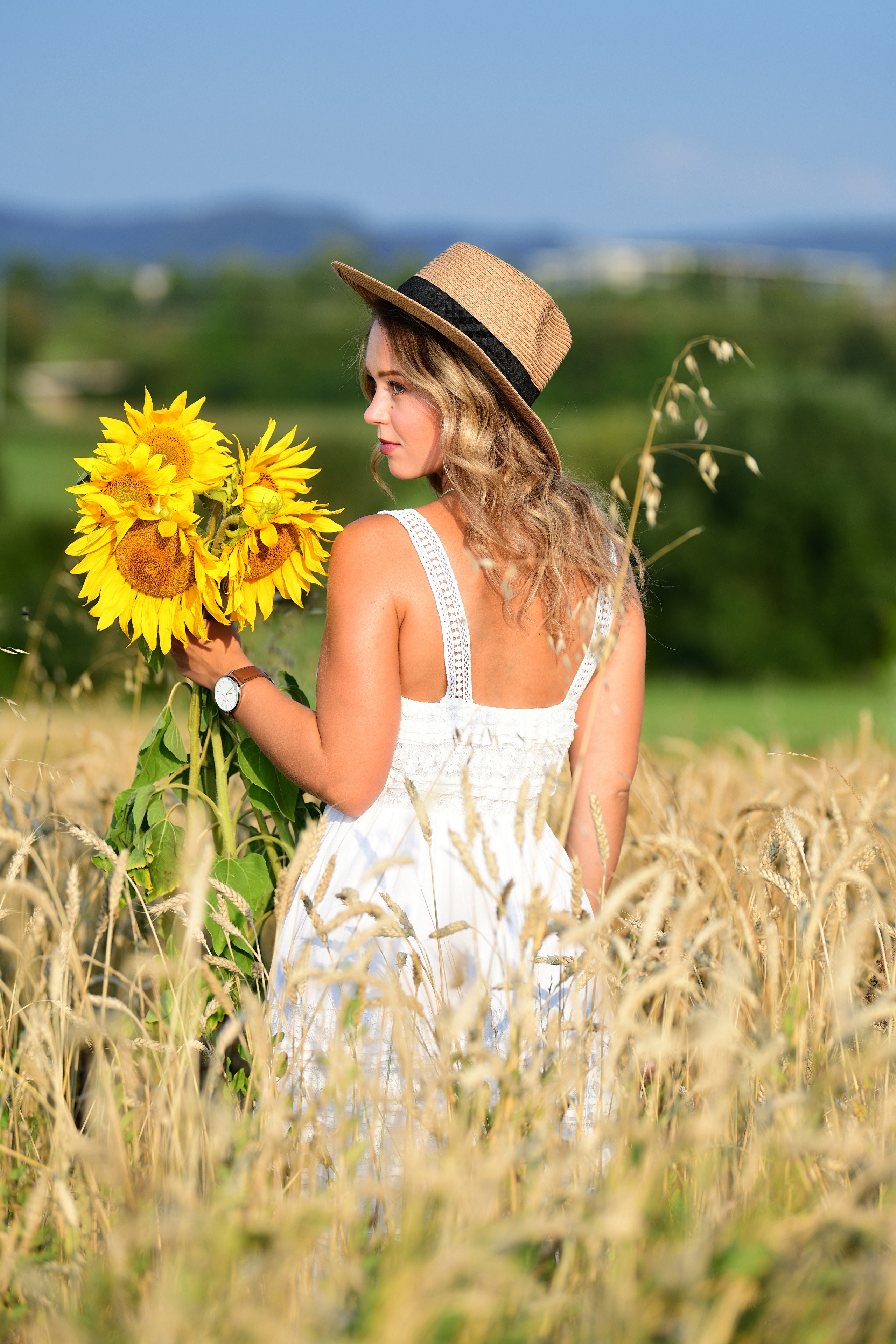 Selina Holding Sunflowers in a Field HD Phone Wallpaper