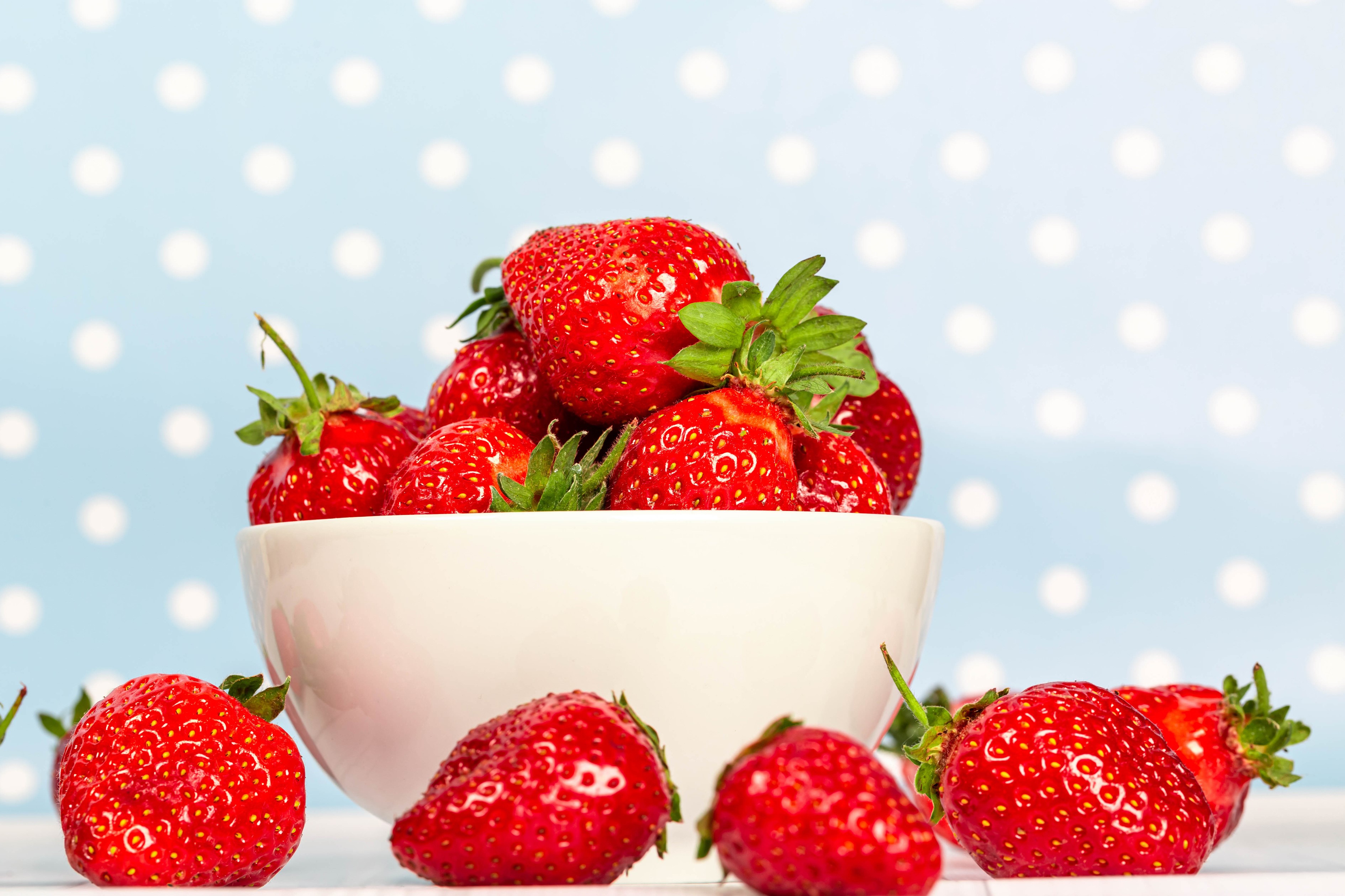 Strawberries in a white bowl on a blue polka dot background HD Wallpaper