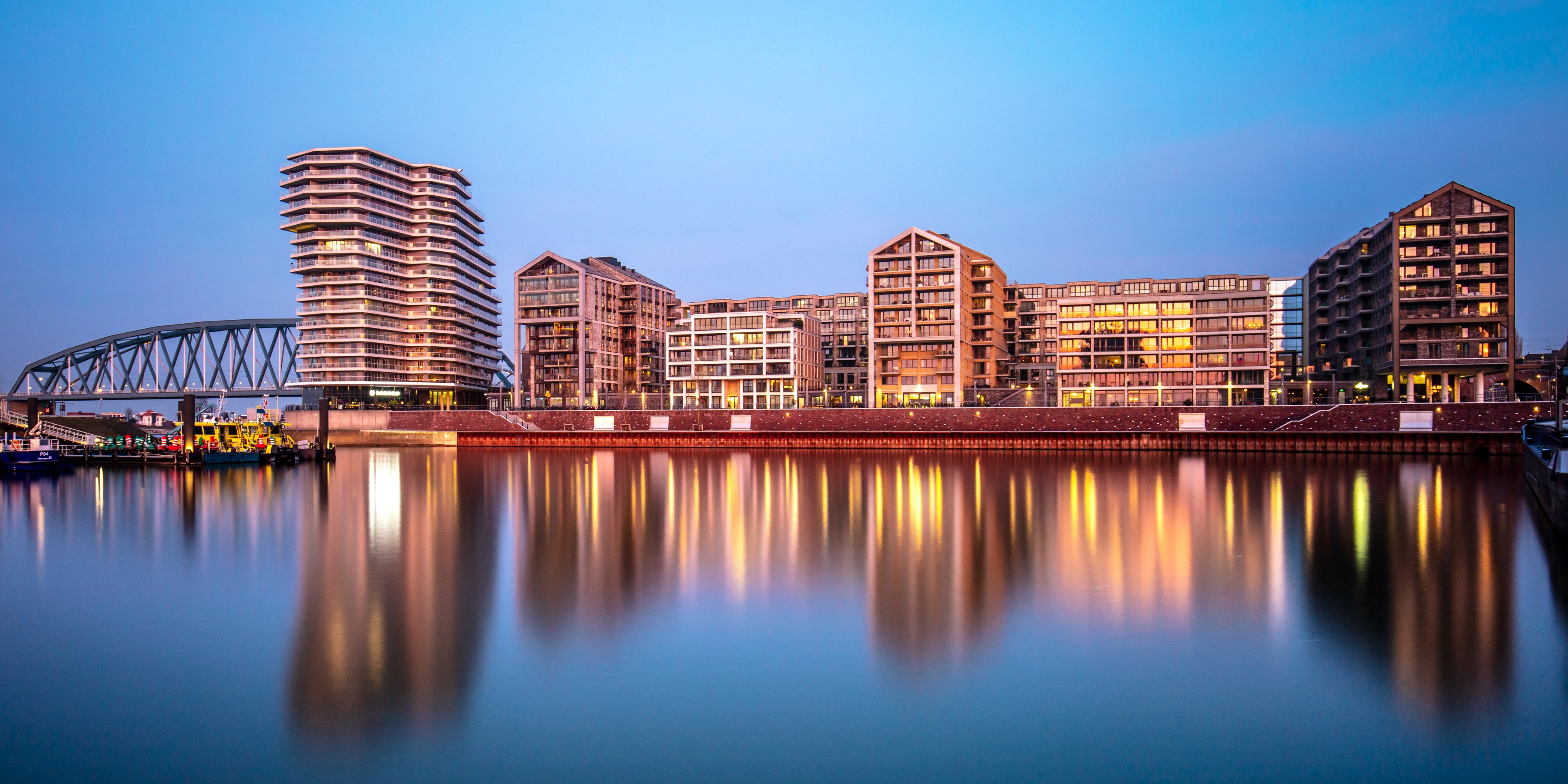 Modern buildings and bridge reflected in water at dusk HD Wallpaper