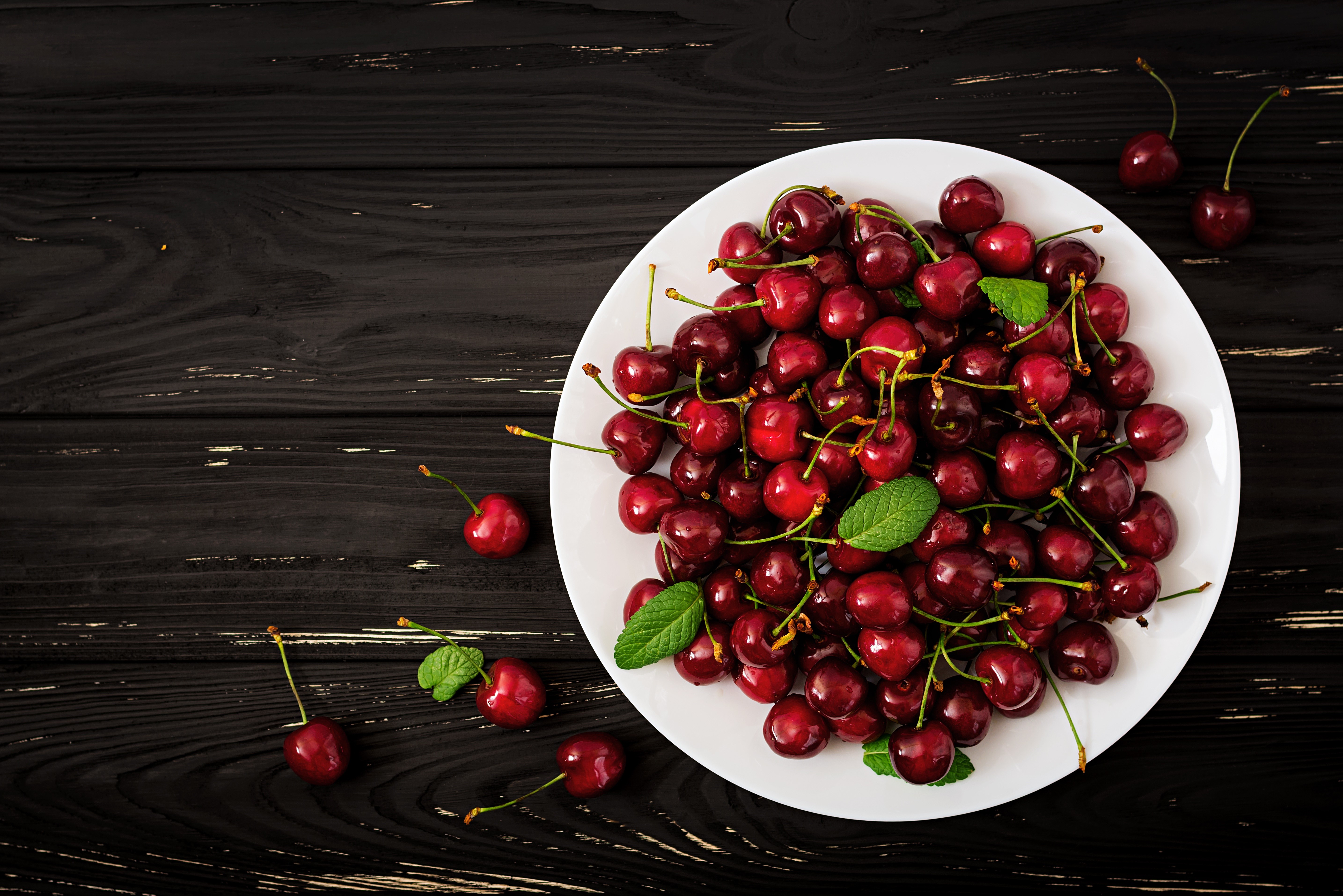 Cherries on a white plate on dark wood planks HD Wallpaper