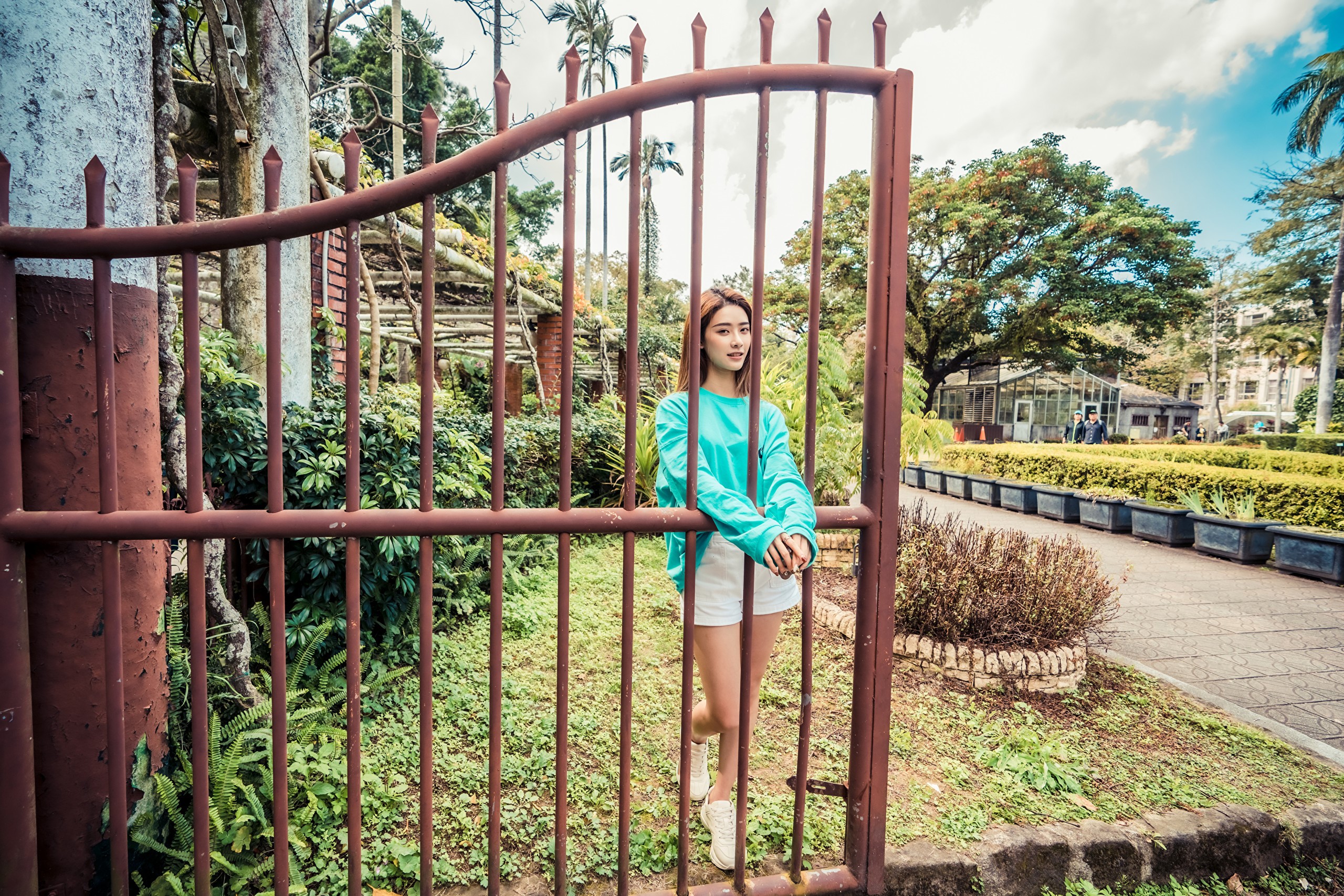 Asian woman in teal shirt and white shorts behind a gate HD Wallpaper