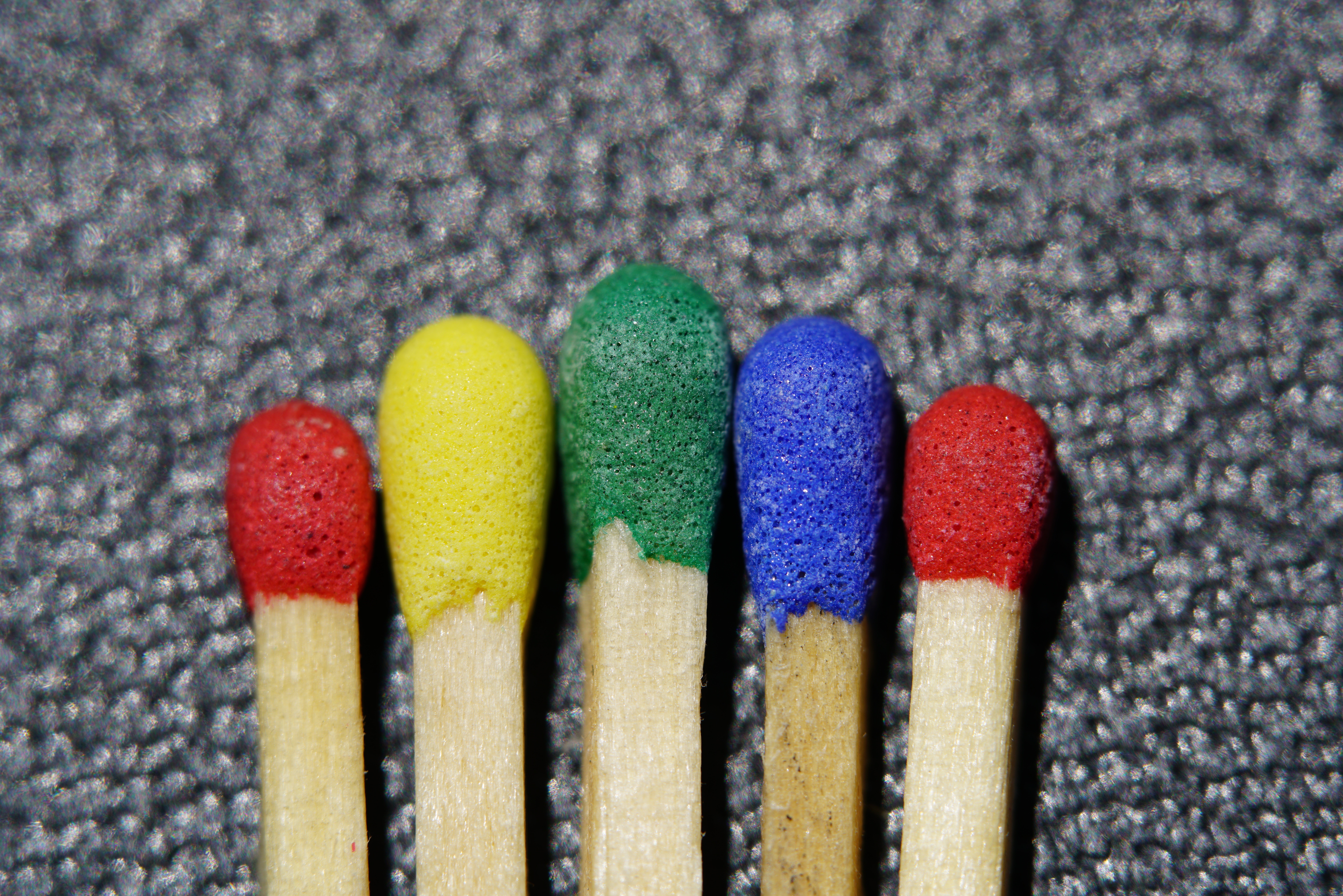 Five multicolored matches on a textured surface HD Wallpaper