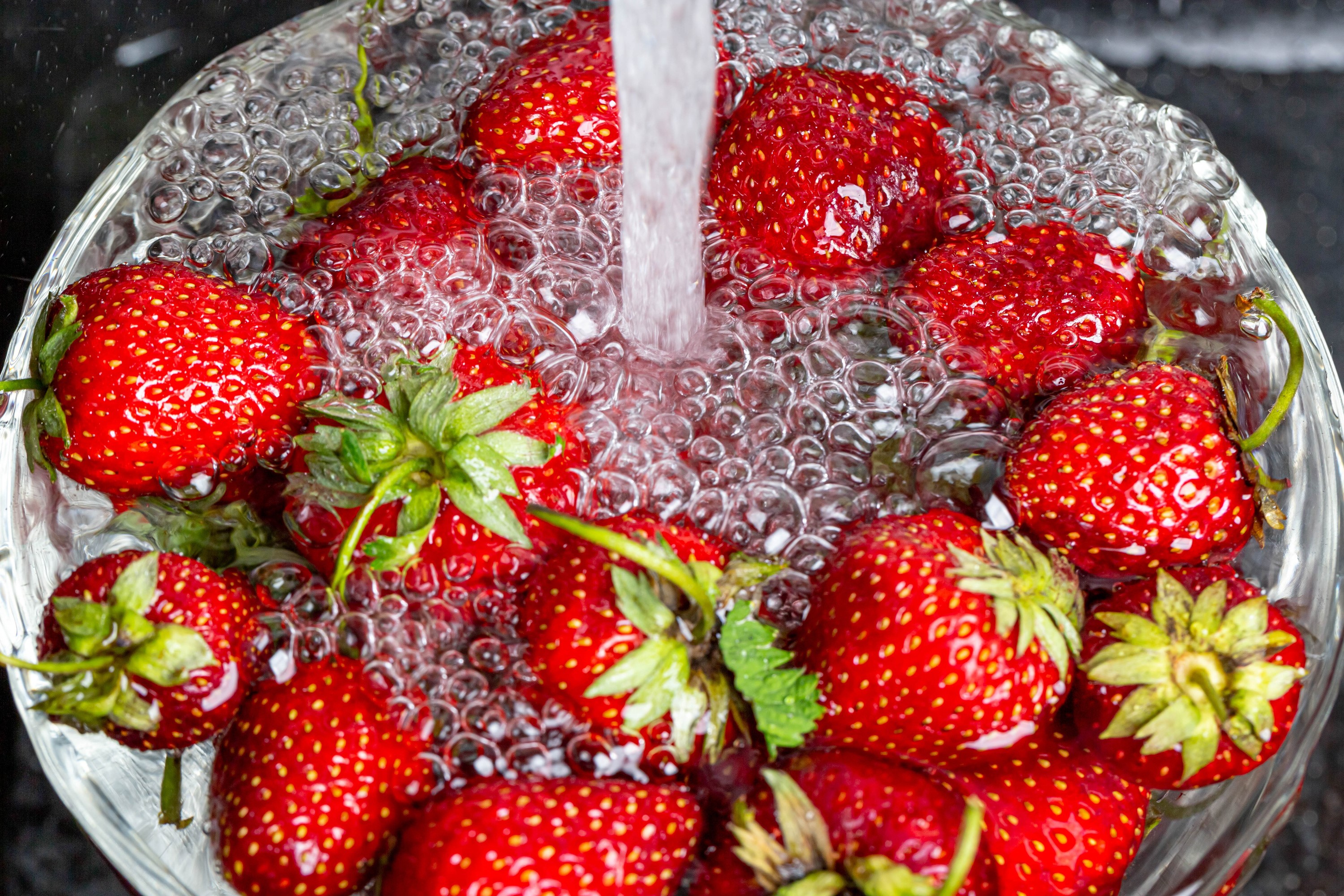Strawberries being washed in a bowl with running water HD Wallpaper