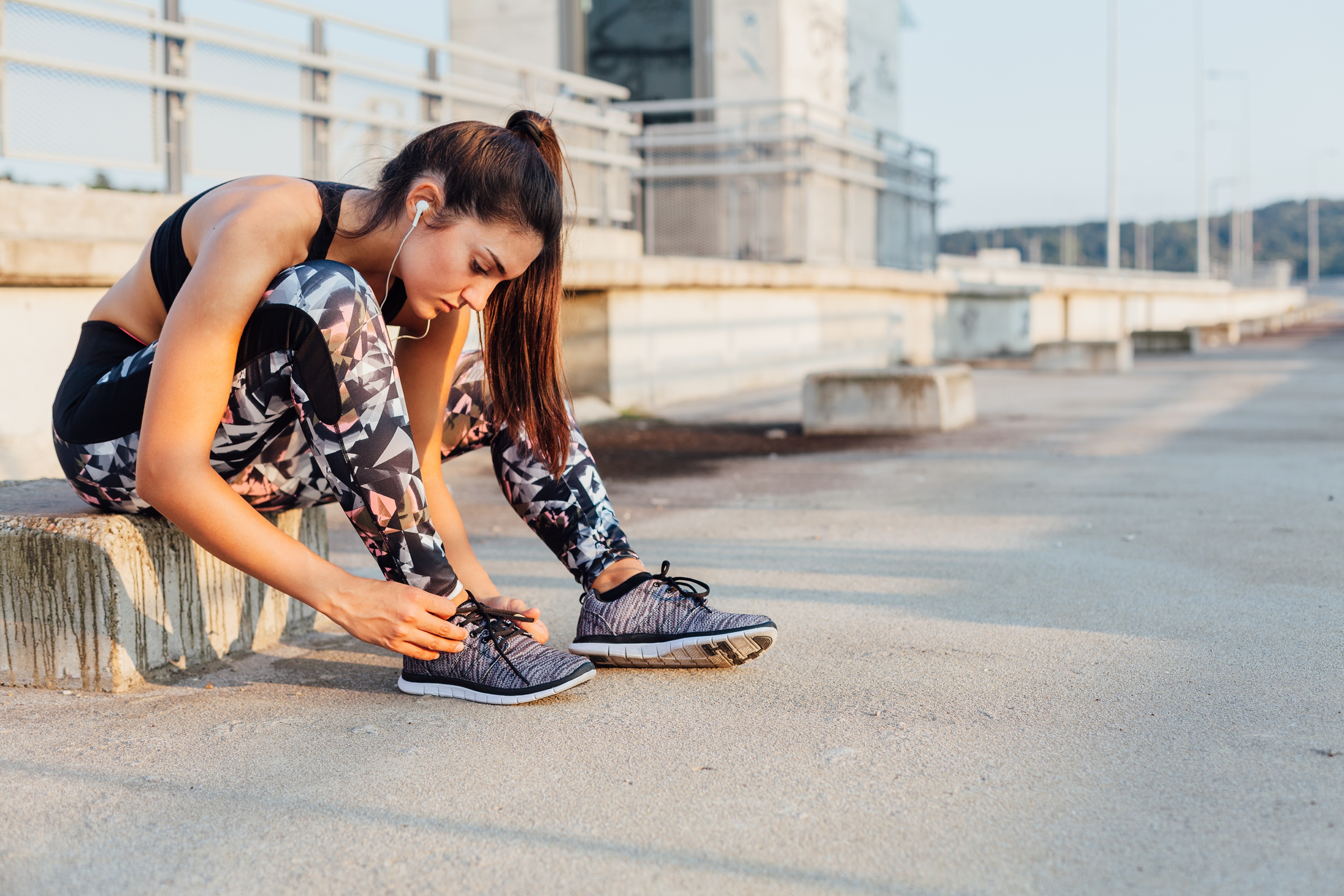Woman tying her athletic shoes outdoors HD Wallpaper