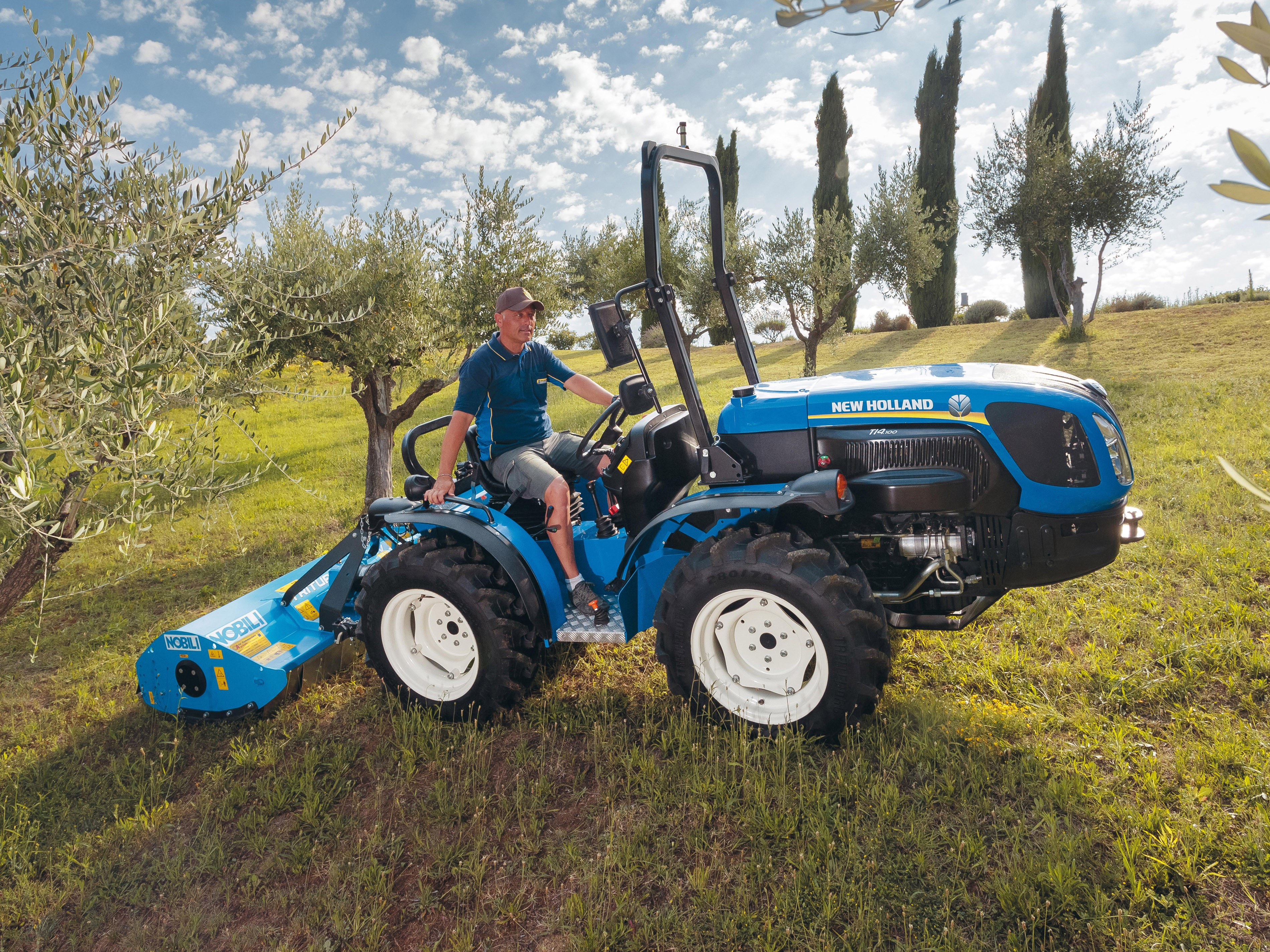 Man driving a New Holland tractor with a tiller HD Wallpaper
