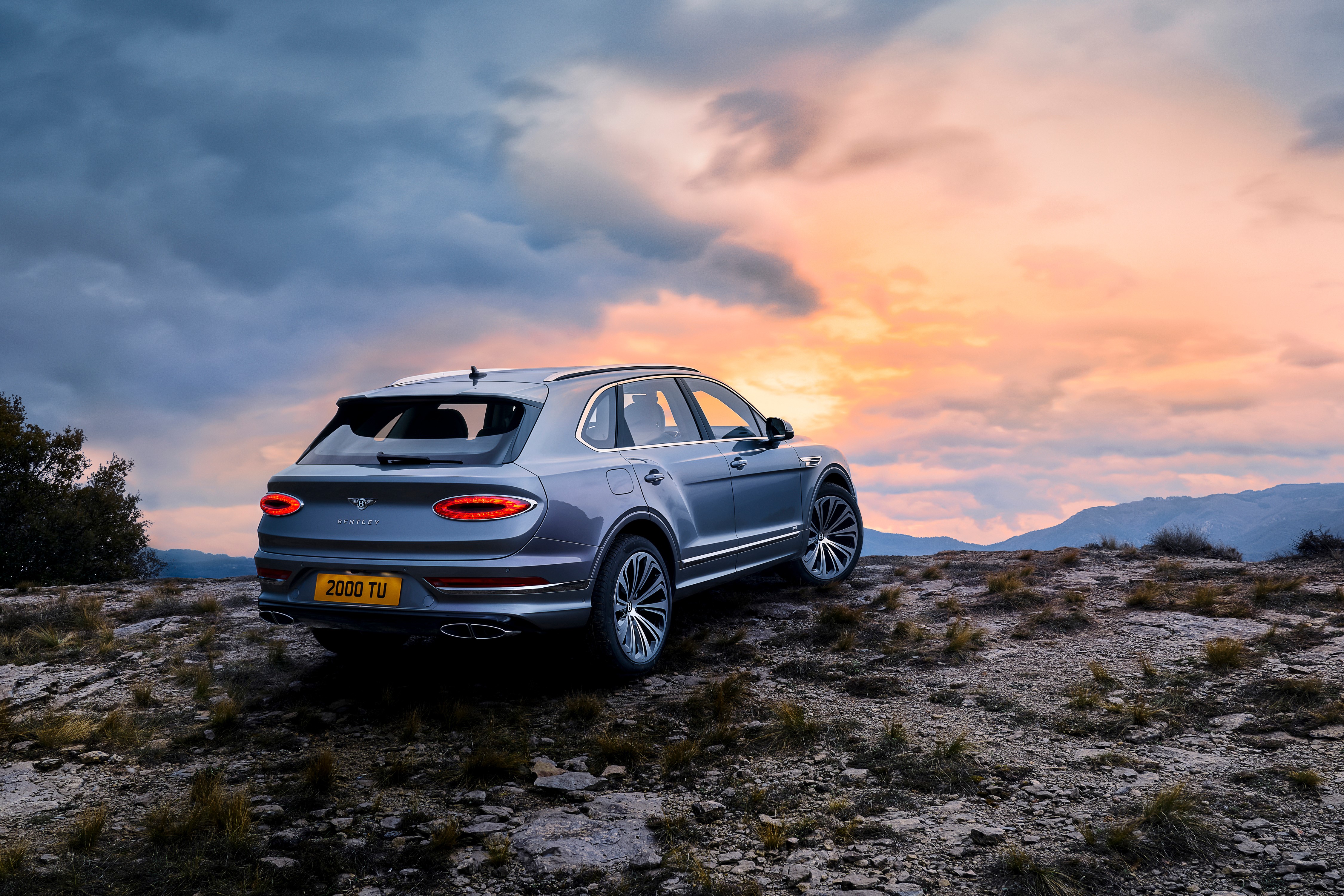 Bentley Bentayga V8 on rocky terrain at sunset HD Wallpaper