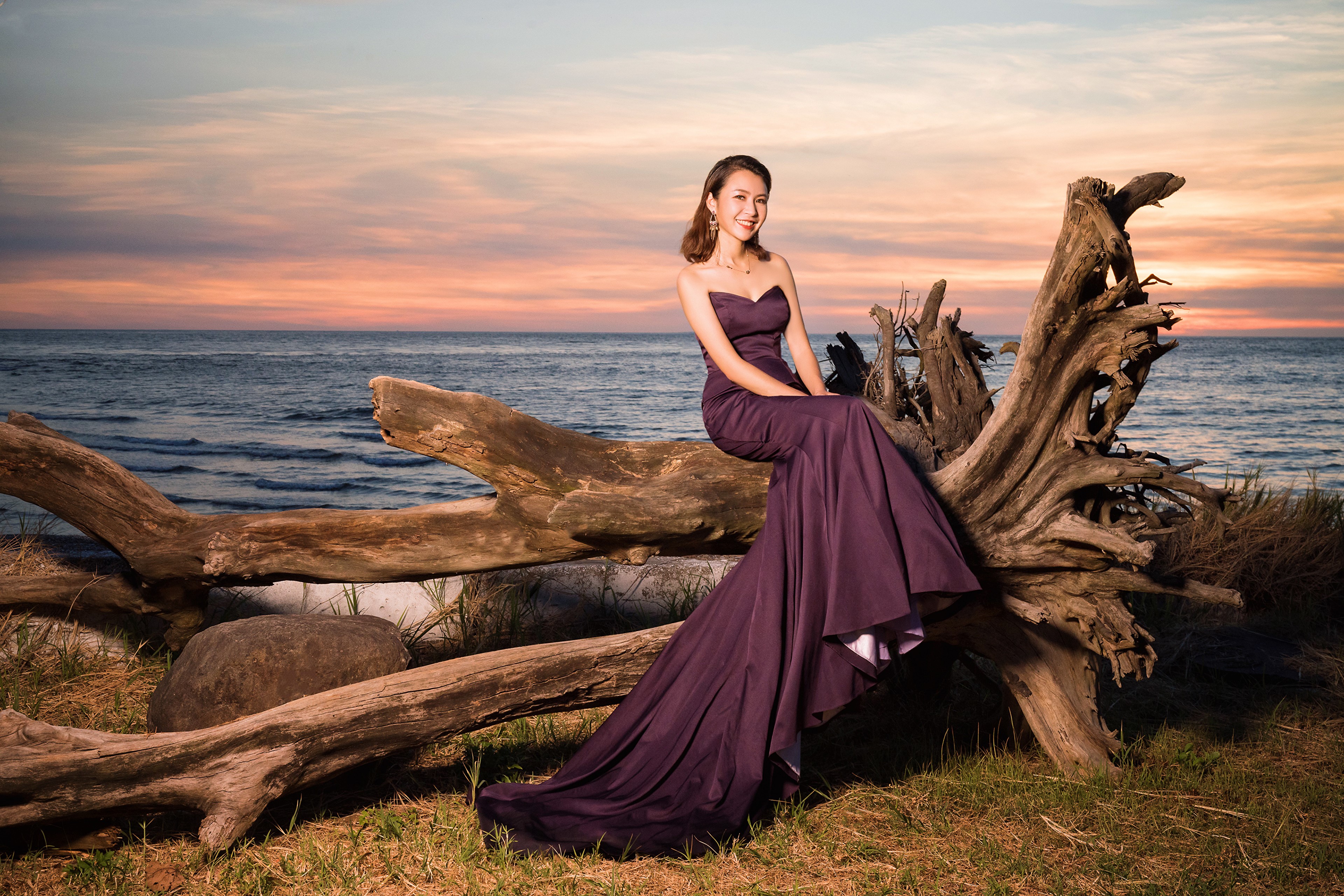 Asian woman in dress sitting on driftwood by the sea HD Wallpaper
