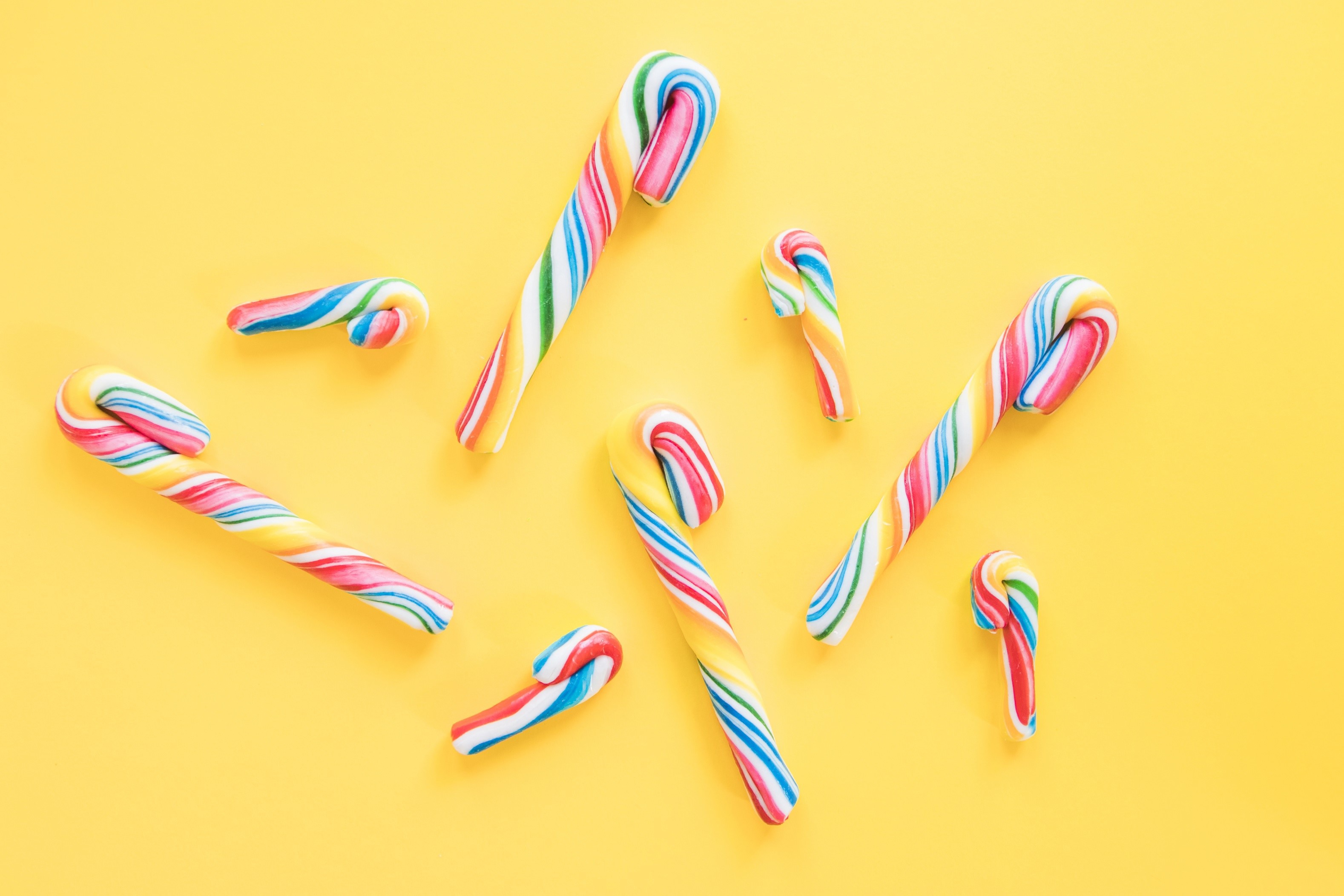 Colorful candy canes on a yellow background HD Wallpaper