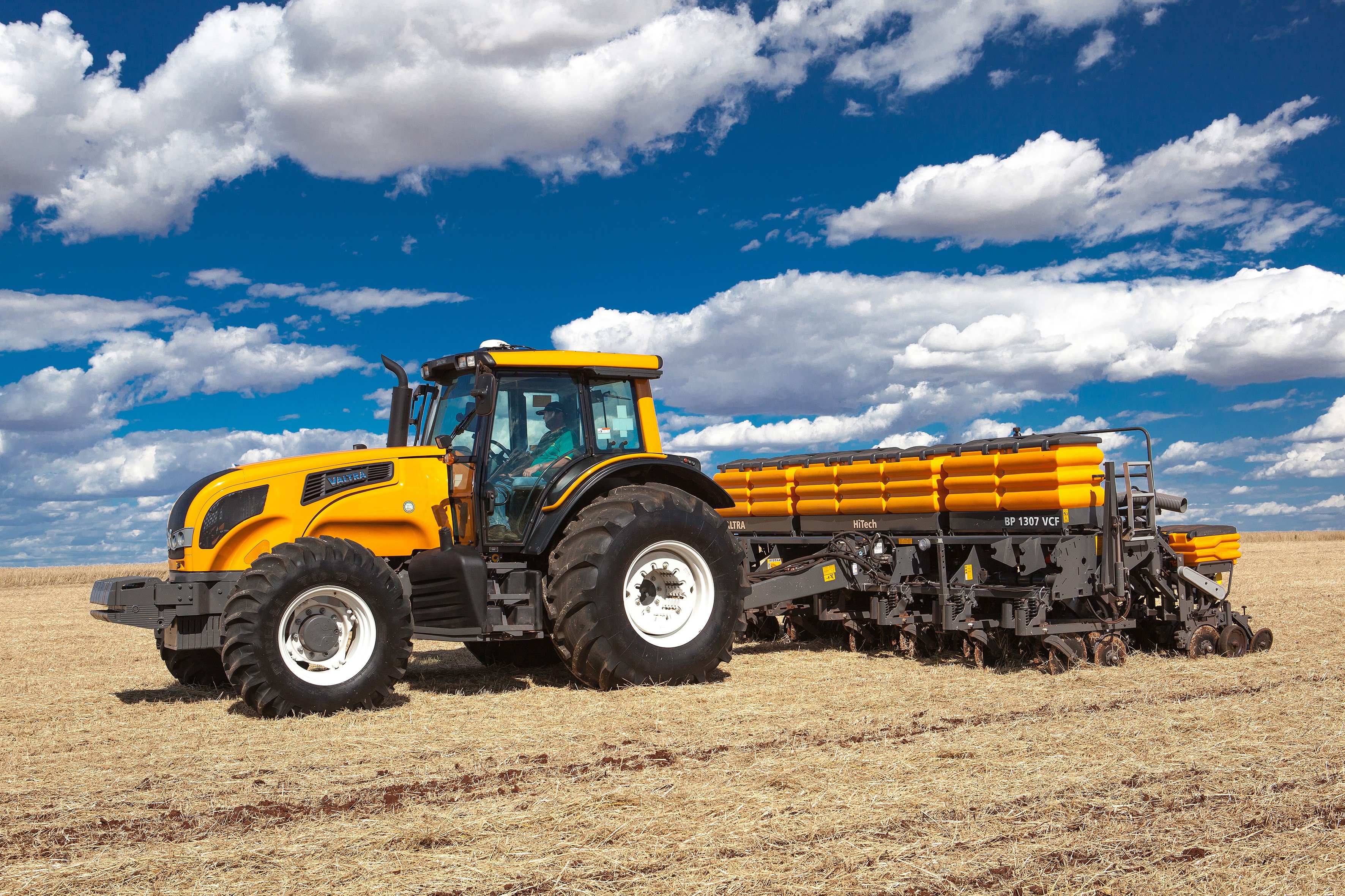 Yellow Valtra tractor pulling a planter in a field HD Wallpaper