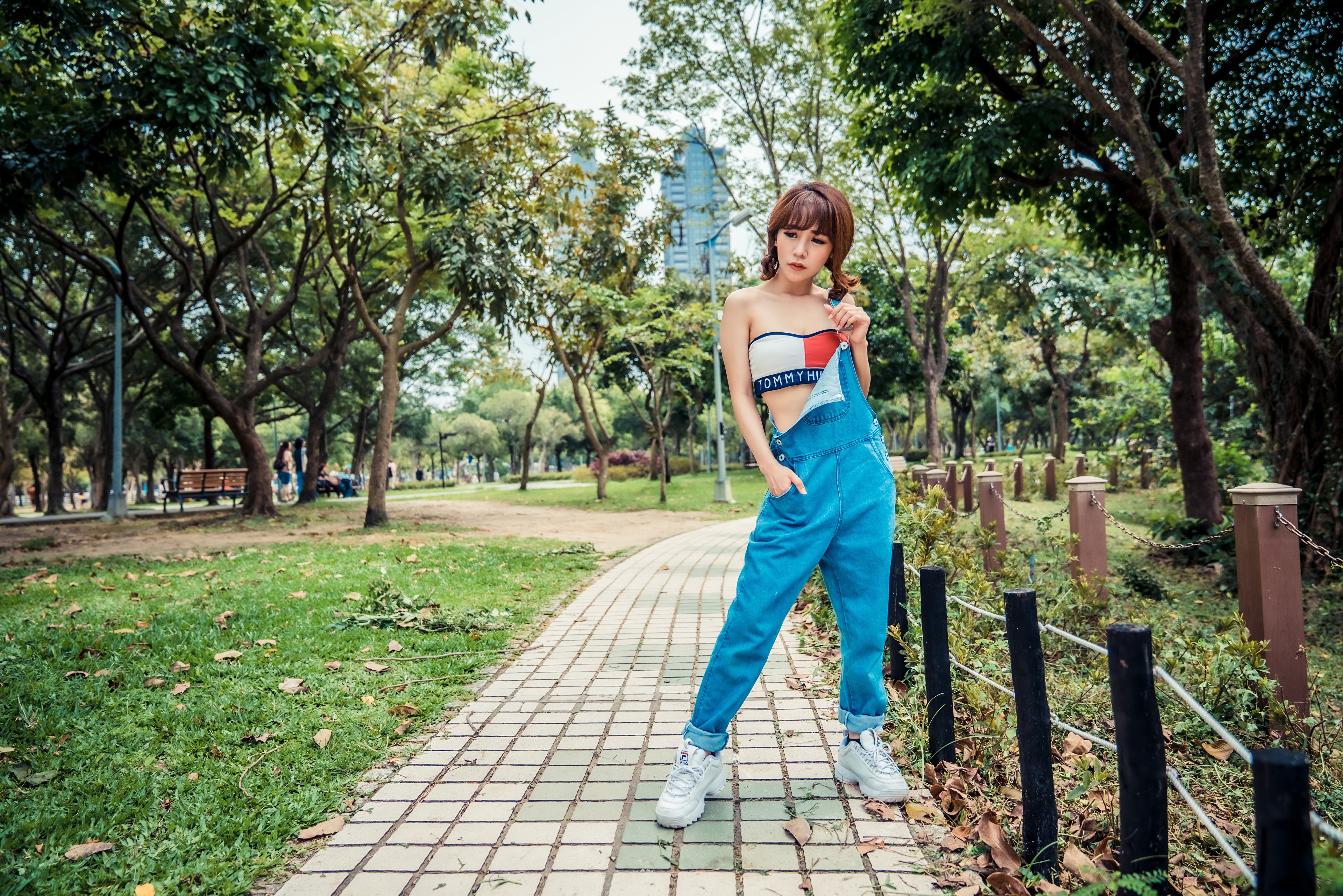 Asian woman in overalls posing in a park HD Wallpaper