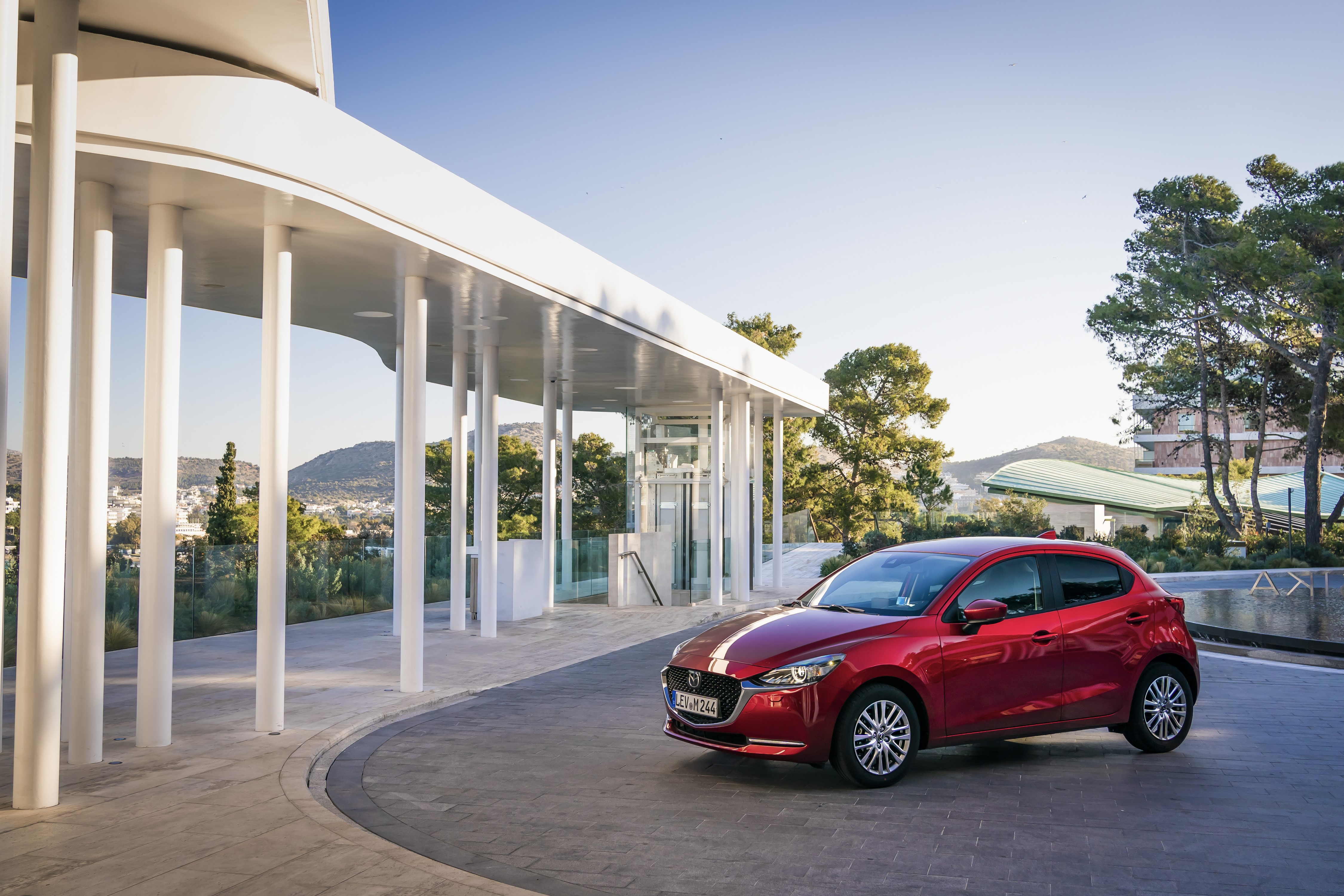 Red 2020 Mazda2 parked near a modern building HD Wallpaper