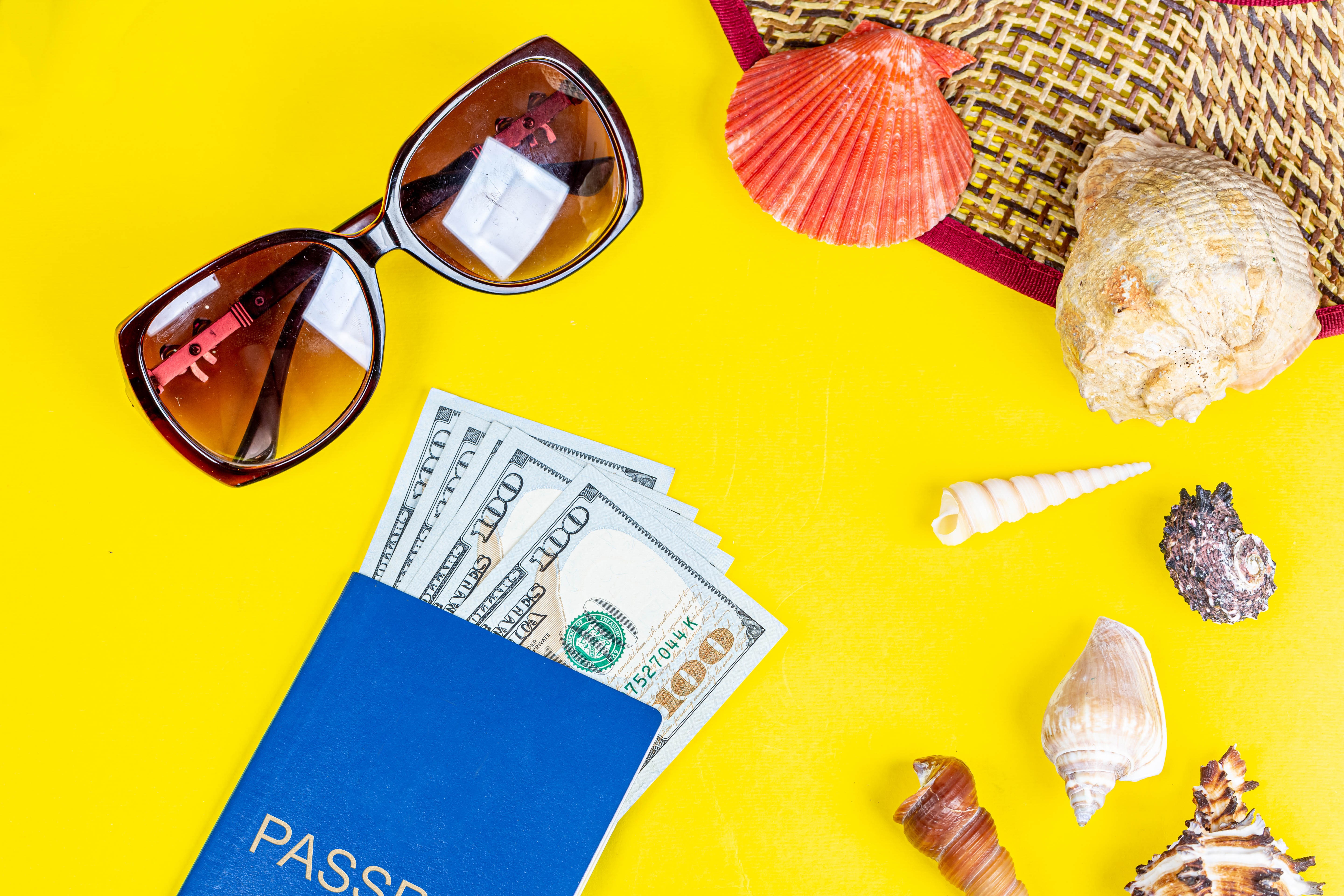 Passport with money, sunglasses, and seashells HD Wallpaper
