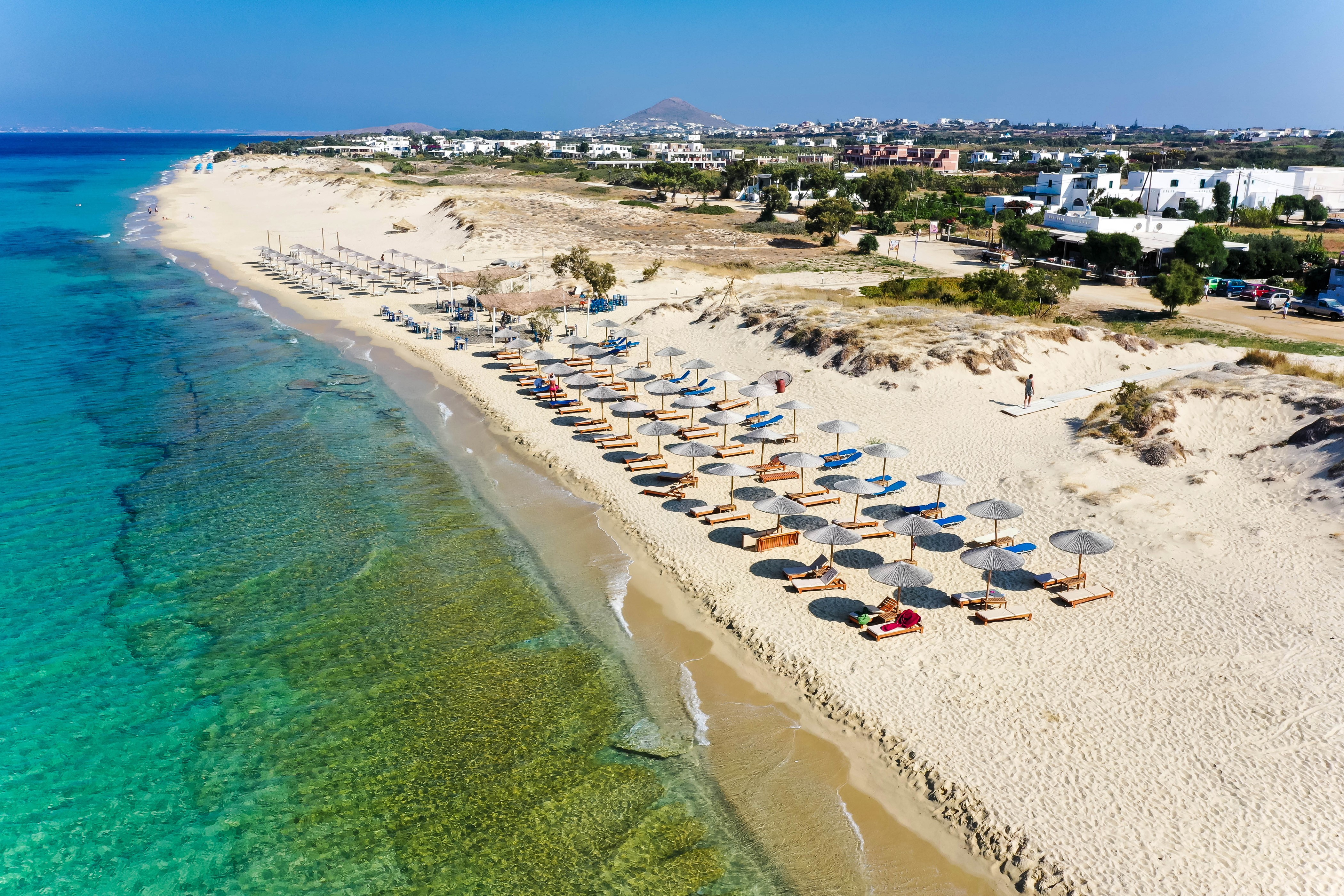 Beach with umbrellas and lounge chairs in Naxos, Greece HD Wallpaper
