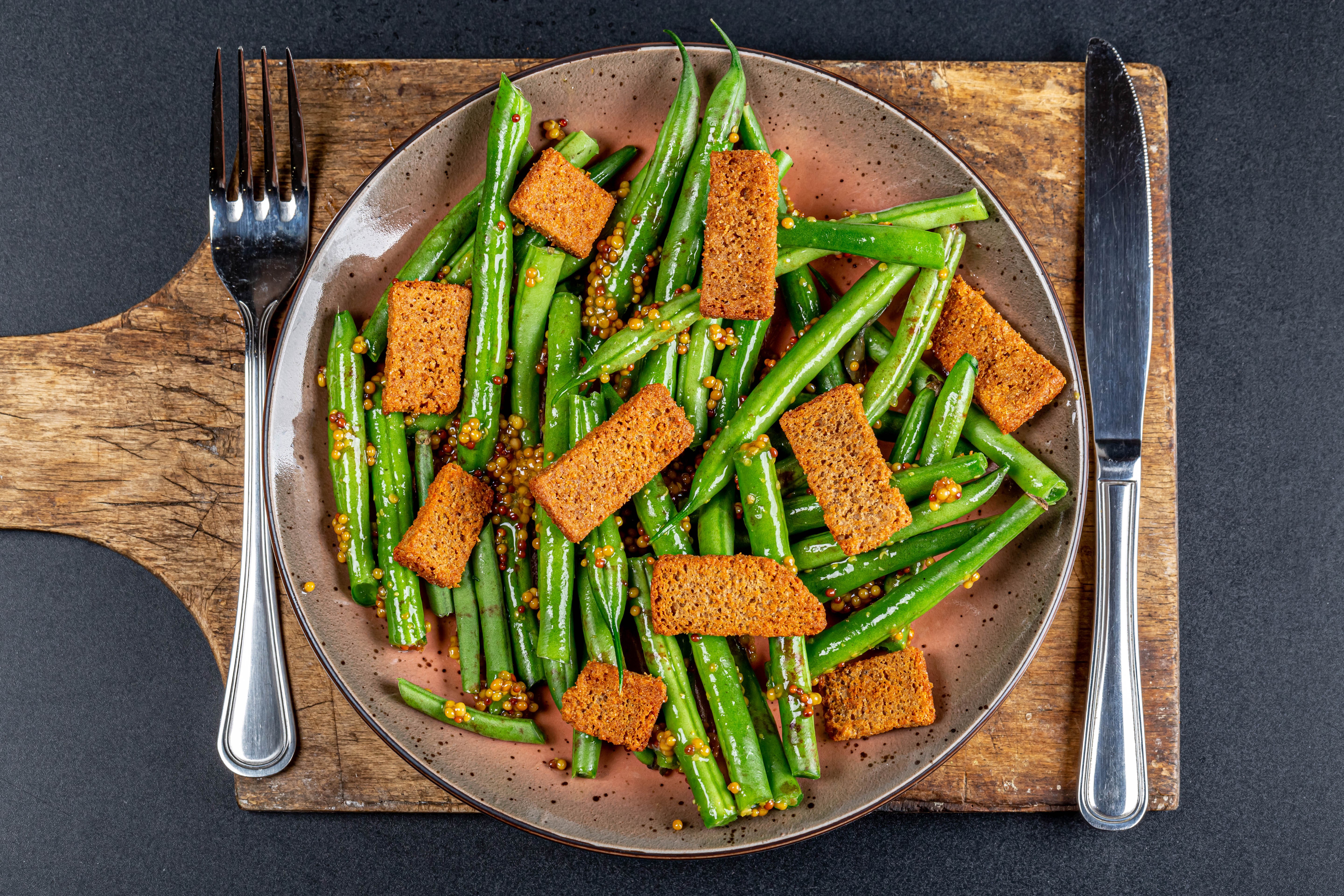 Green beans with croutons on a plate with fork and knife HD Wallpaper