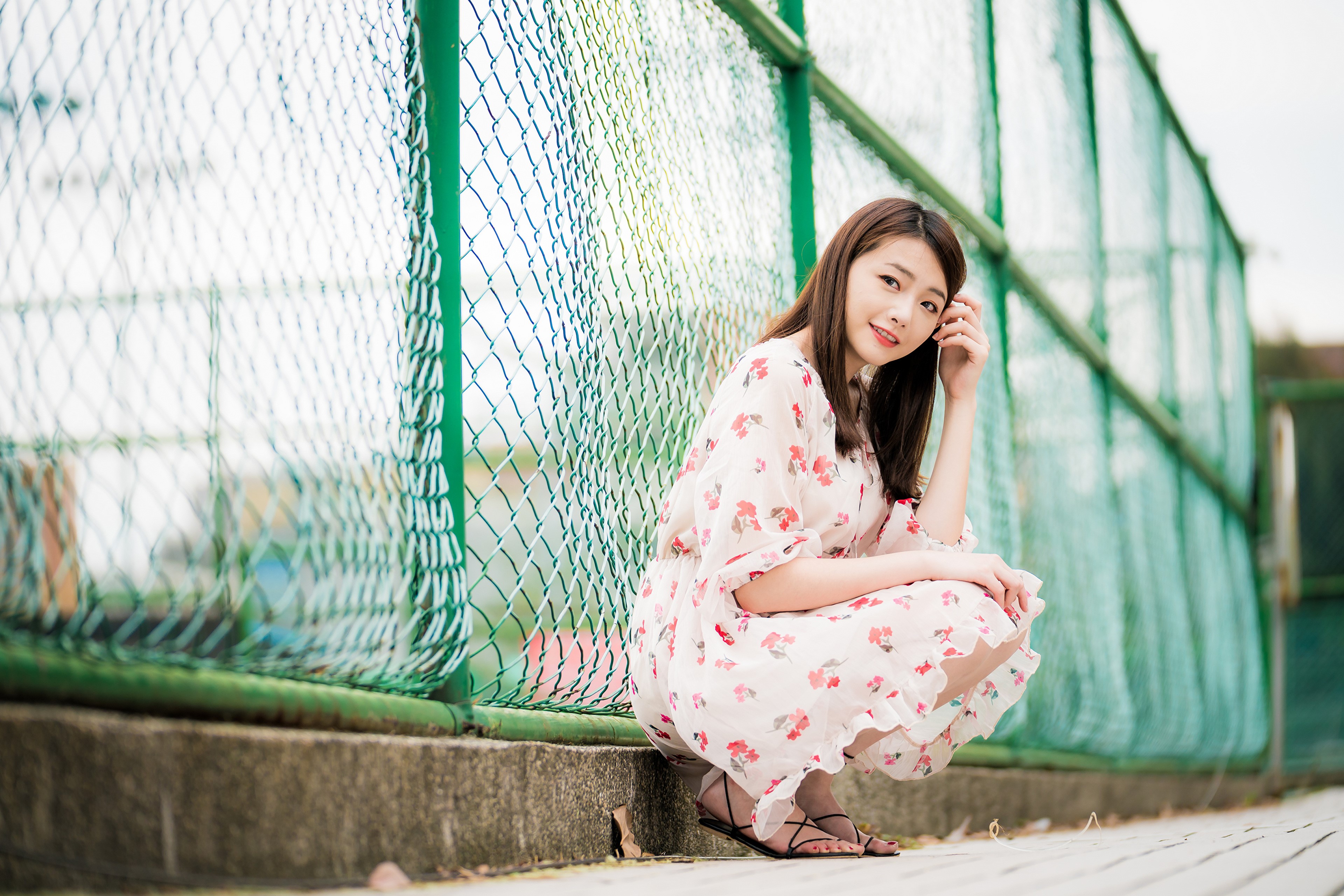 Asian woman in floral dress by fence HD Wallpaper