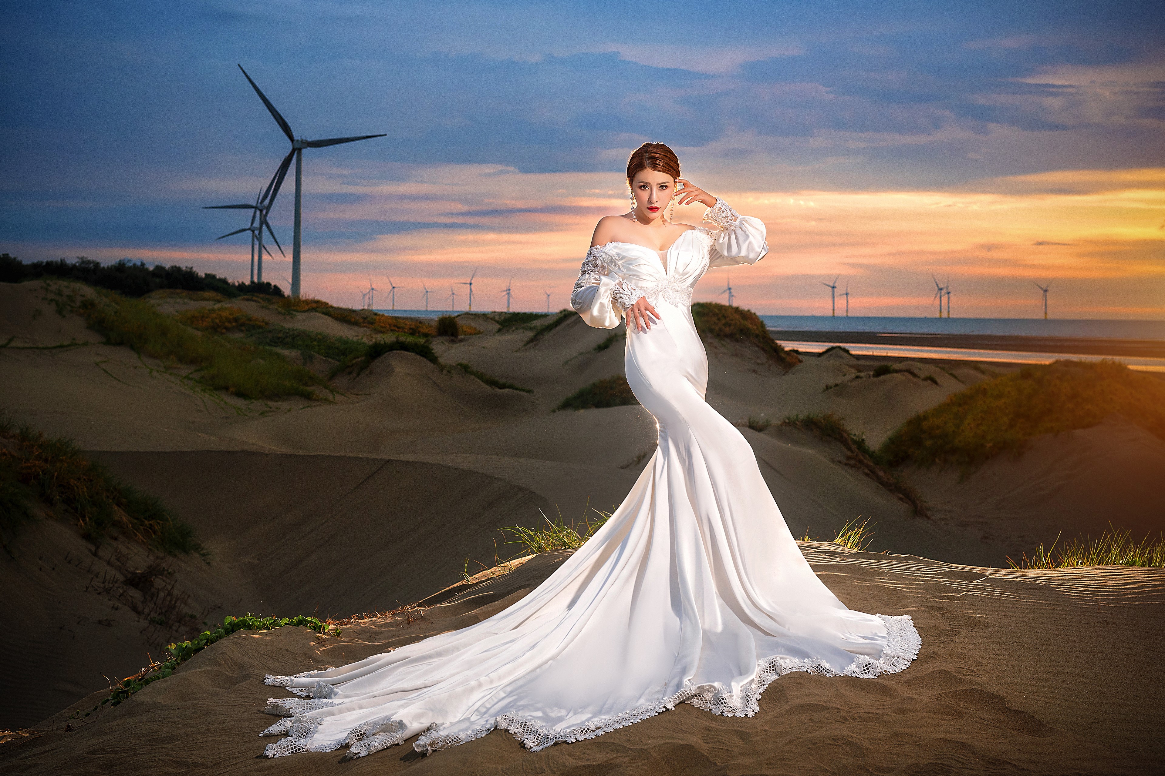 Asian woman in wedding dress posing near wind turbines HD Wallpaper