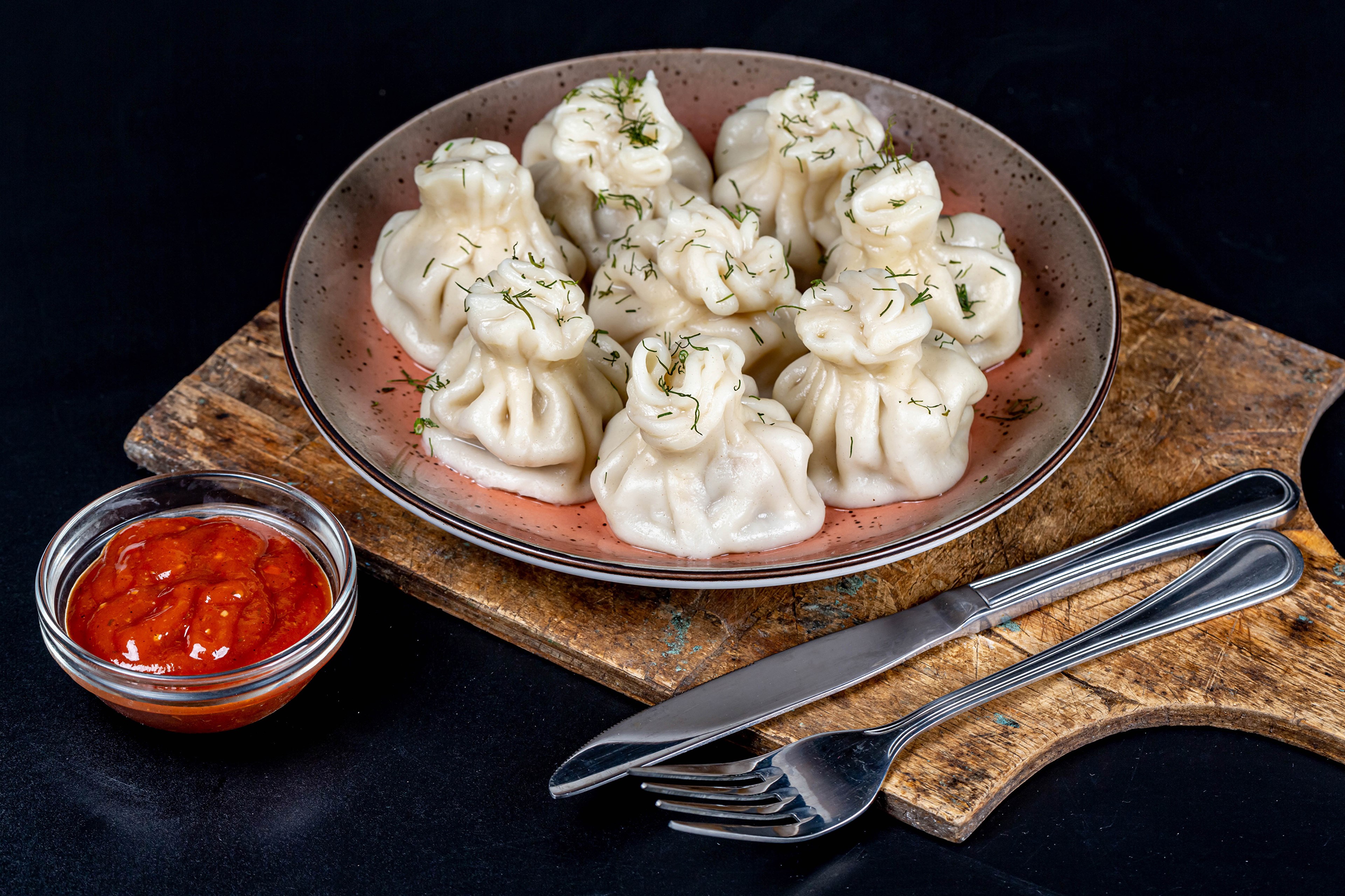 Khinkali dumplings with dill and ketchup on a cutting board HD Wallpaper