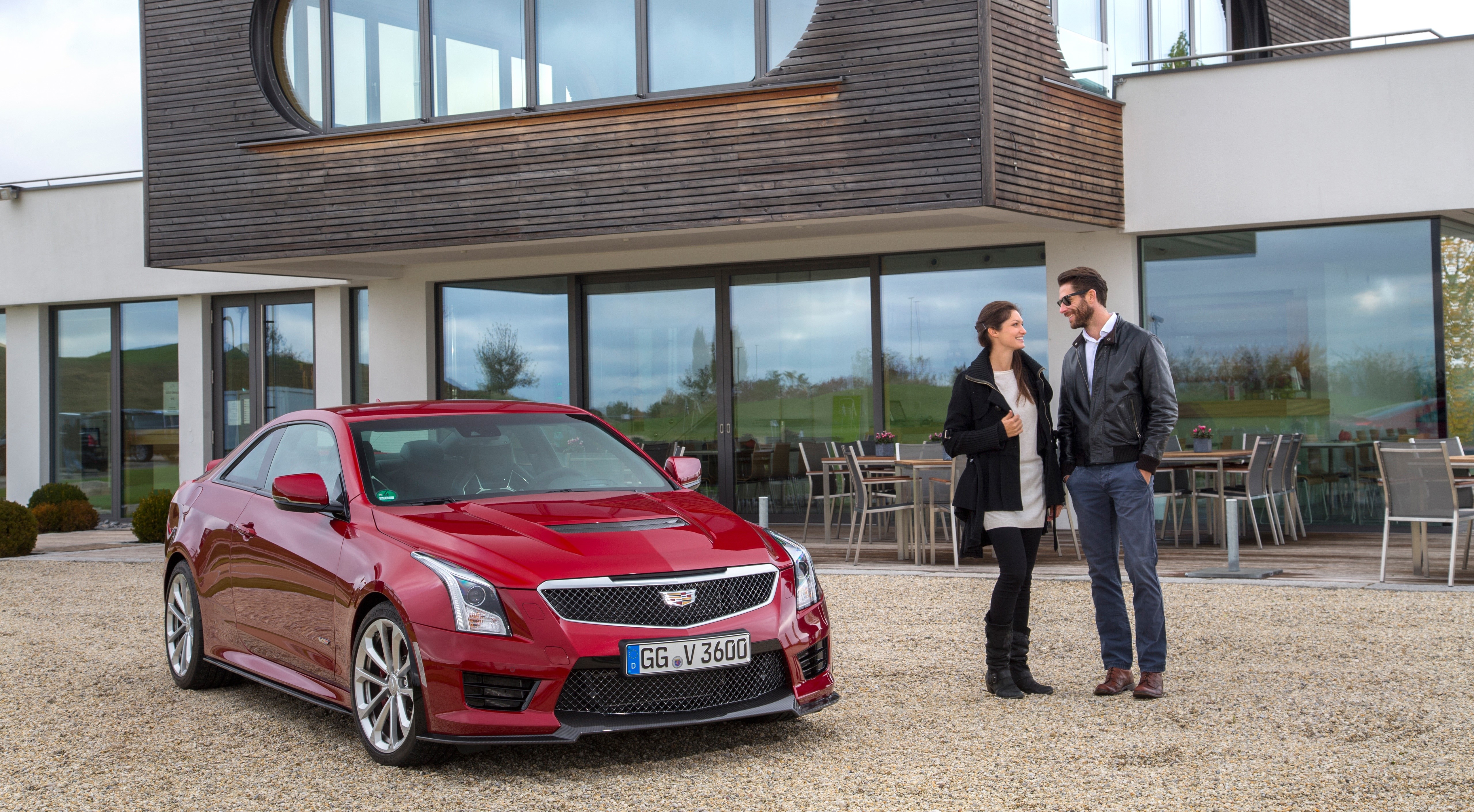Red Cadillac ATS-V Coupe with Couple in front of Modern Building HD Wallpaper