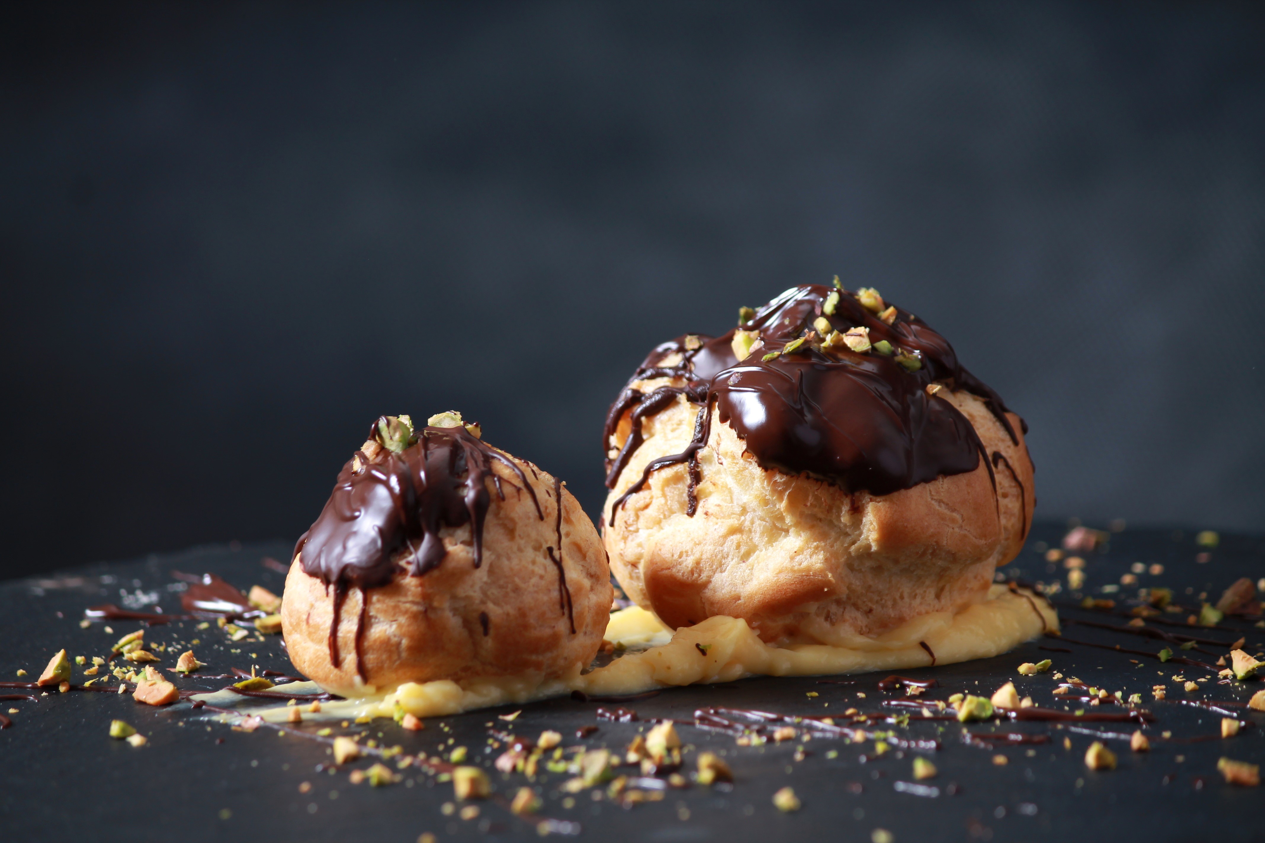 Two chocolate cream puffs with pistachios HD Wallpaper