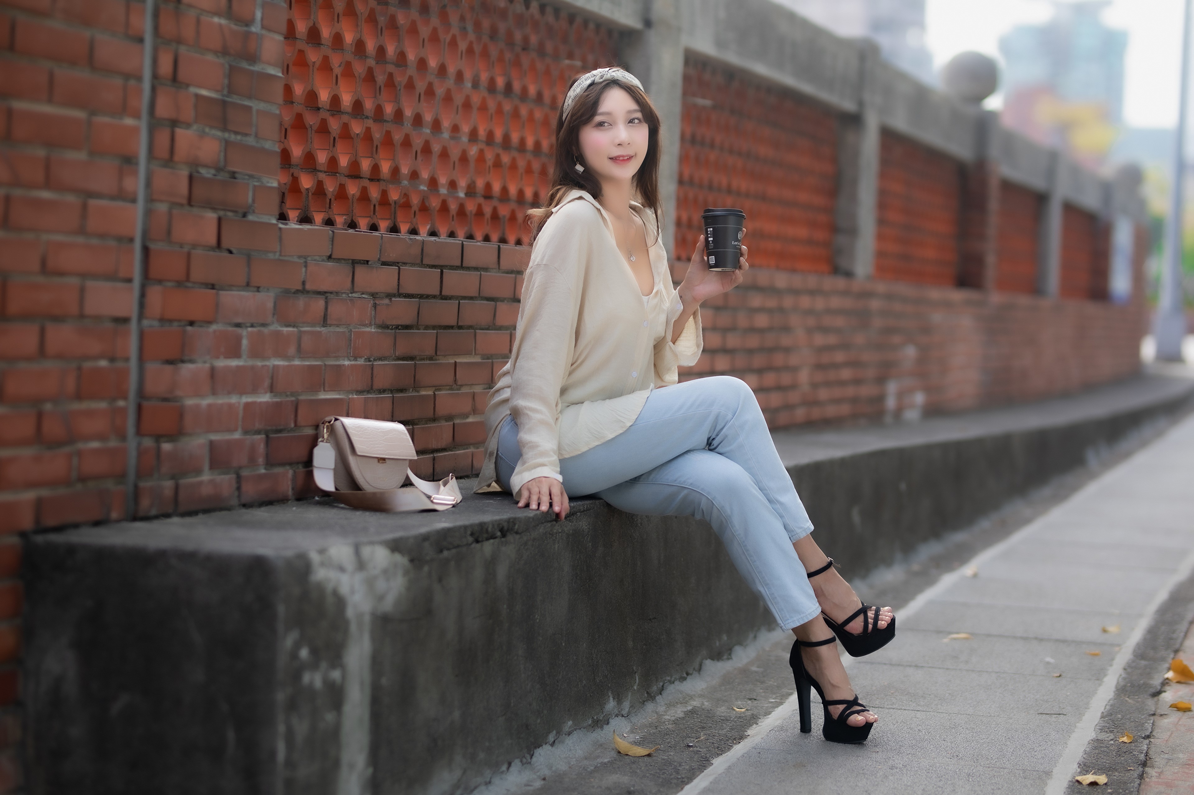 Woman in Jeans and Heels Sitting by Brick Wall HD Wallpaper