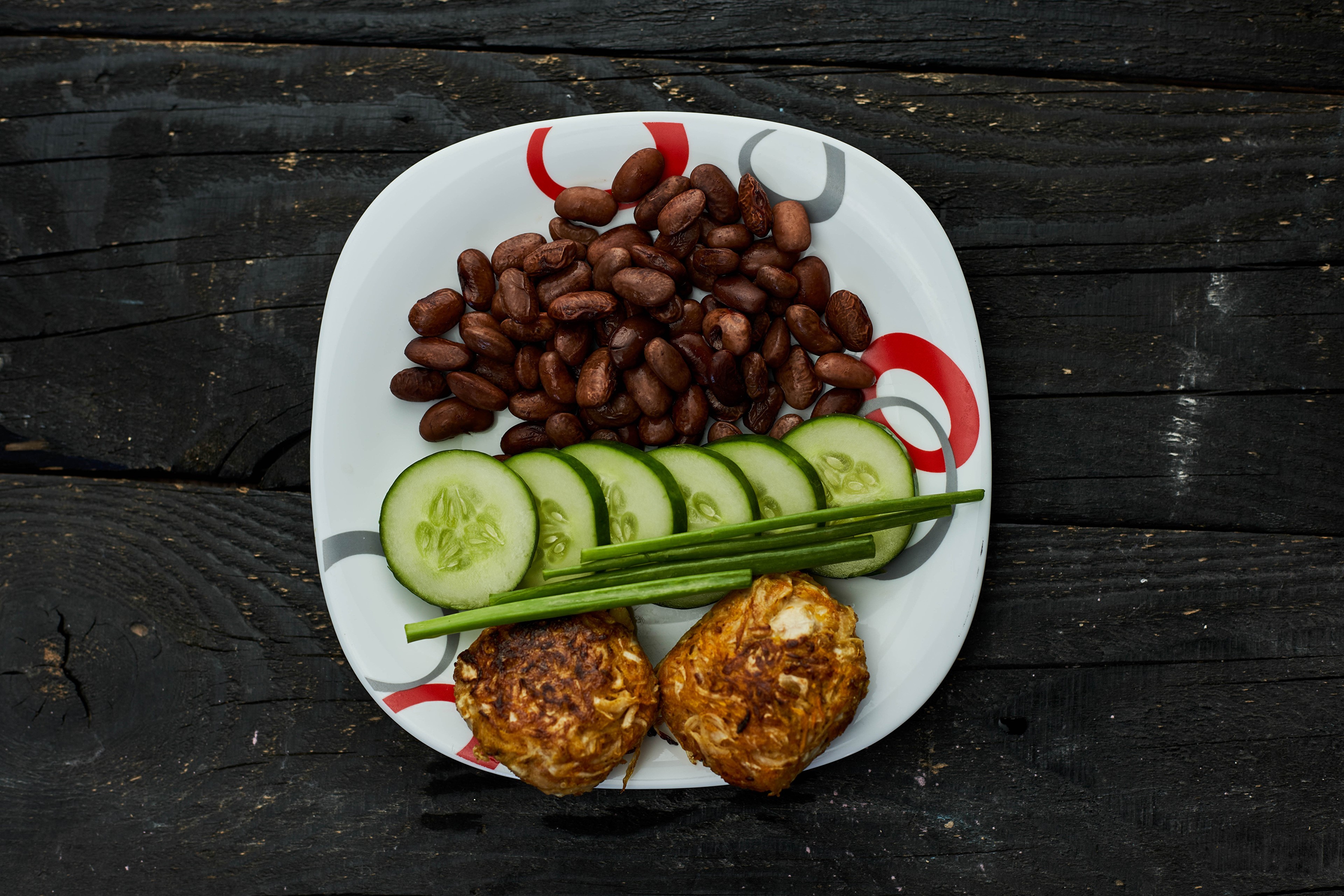 Plate of beans, cucumber slices, and patties on wood HD Wallpaper