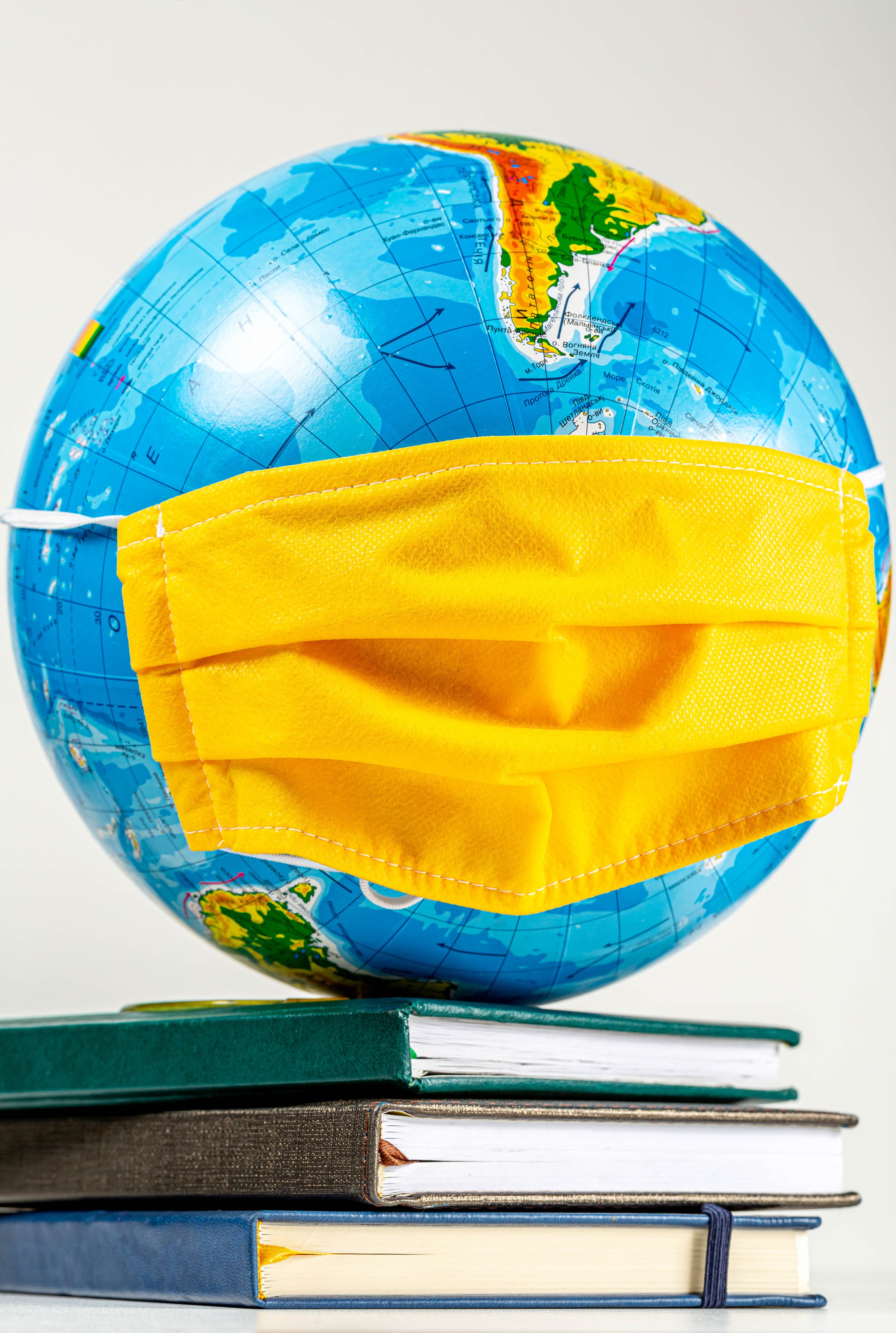 Globe wearing a face mask on books HD Phone Wallpaper
