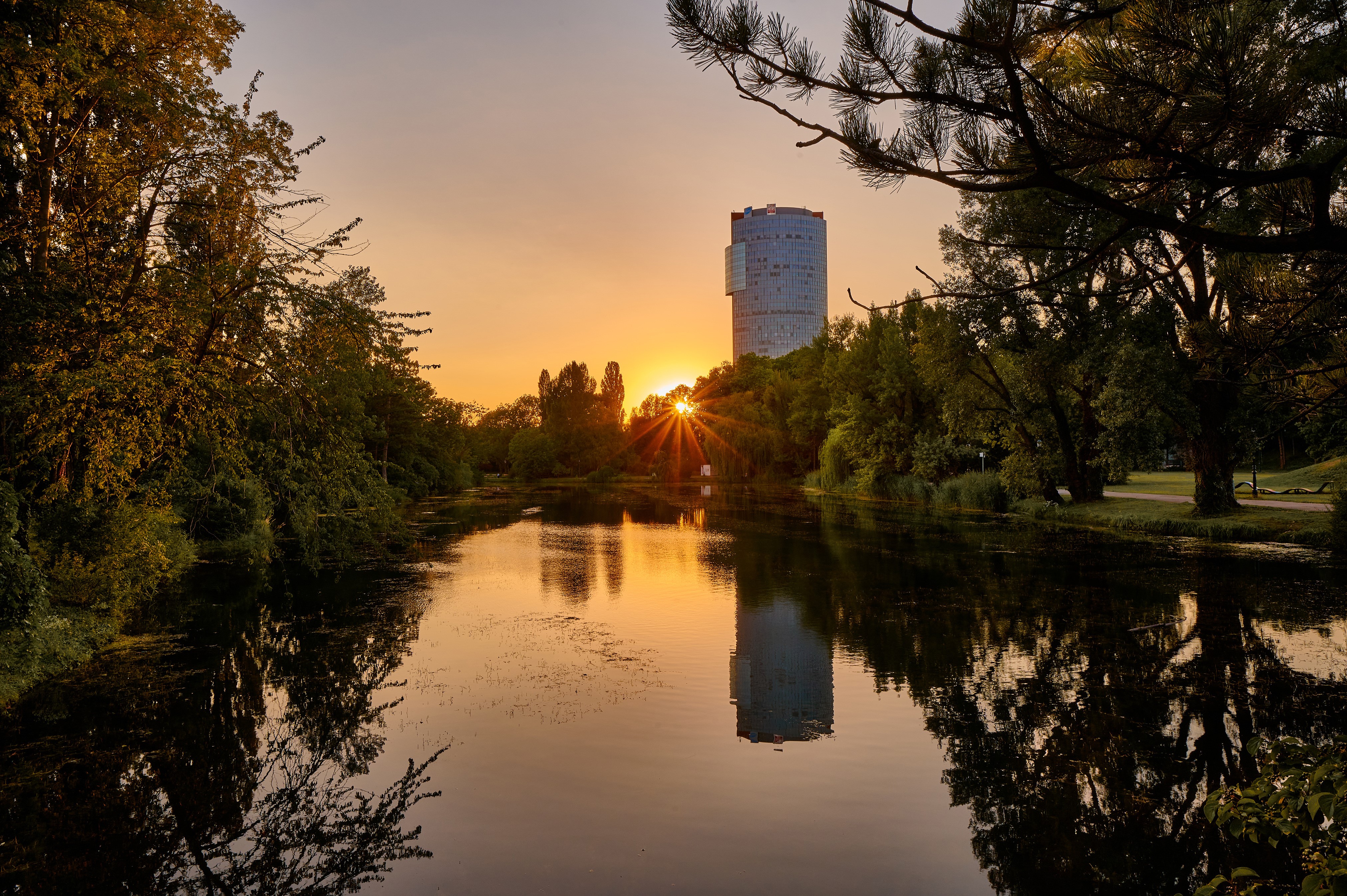 Sunset over a pond with a tall building in Vienna, Austria HD Wallpaper