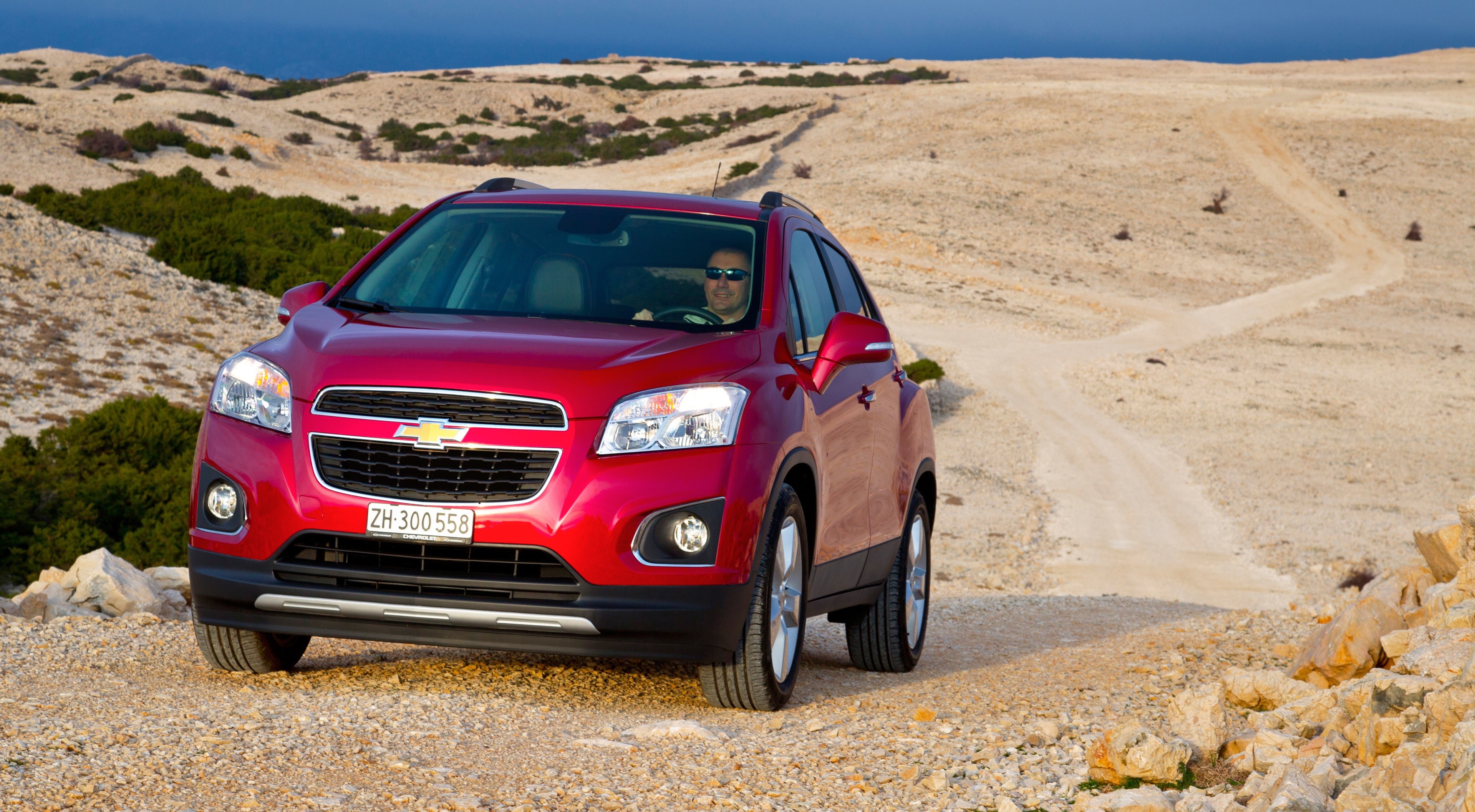 Red Chevrolet Trax Crossover on a dirt road HD Wallpaper
