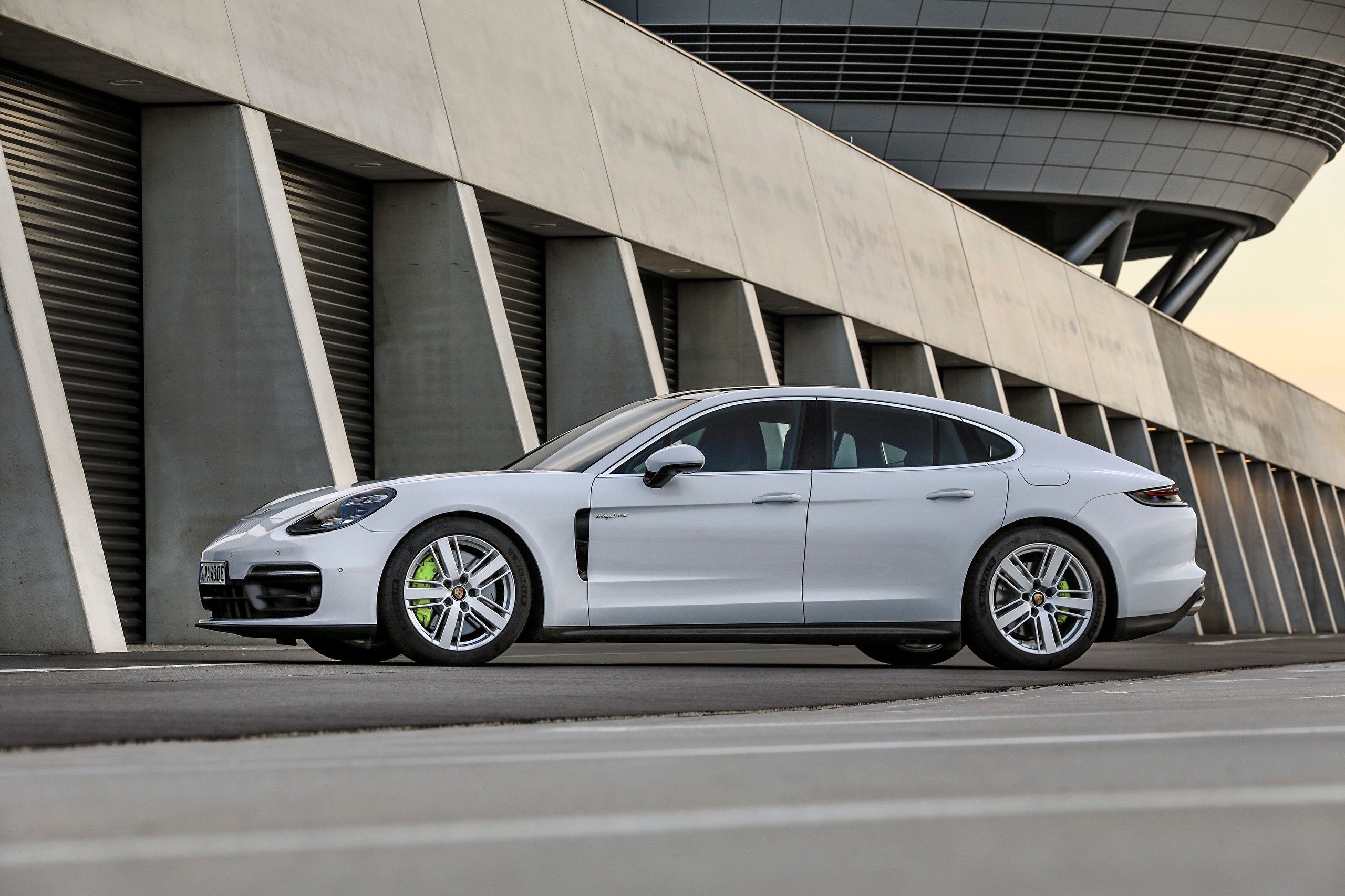 White Porsche Panamera 4S E-Hybrid parked outside a modern building HD Wallpaper