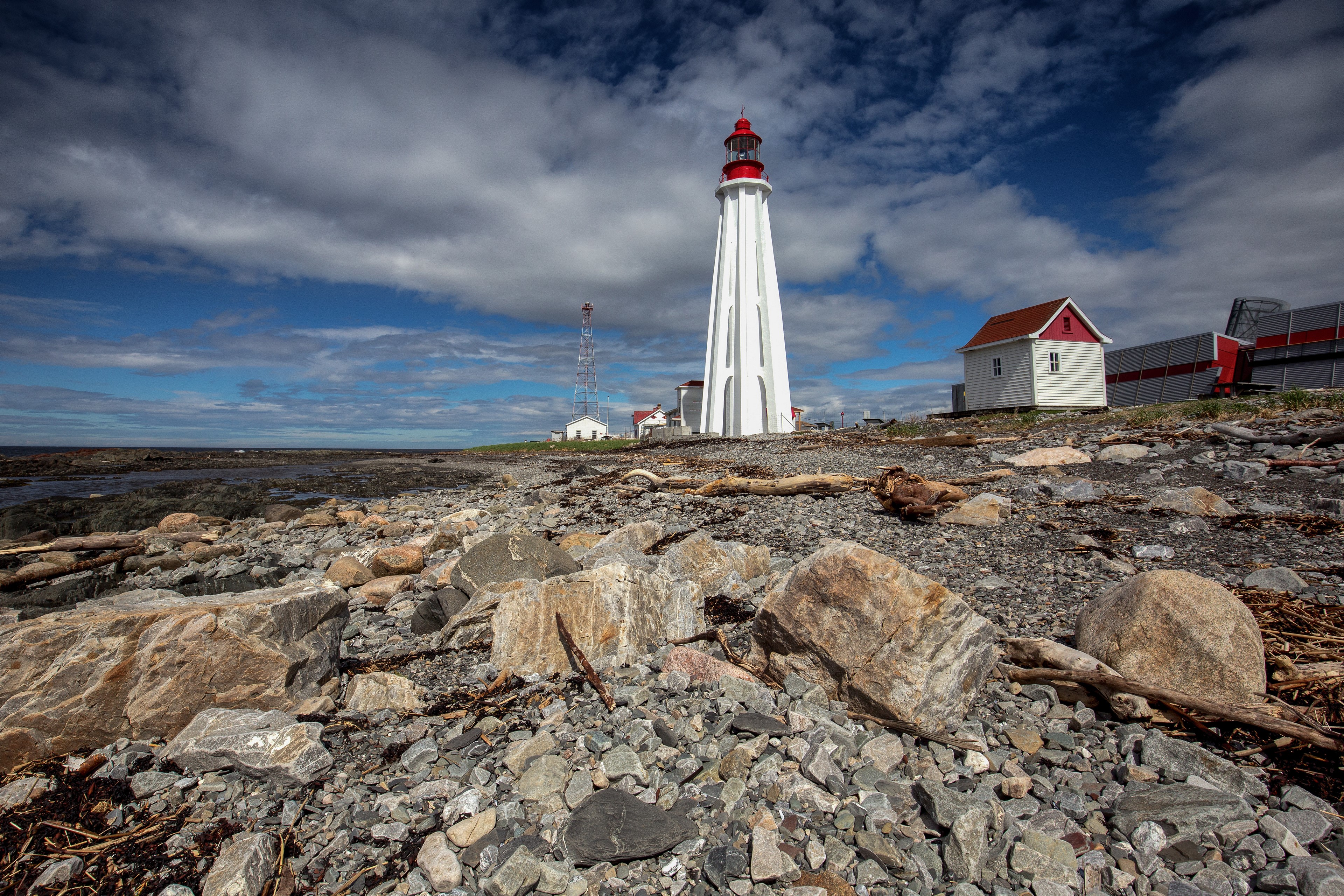 White lighthouse on a rocky shore in Canada HD Wallpaper