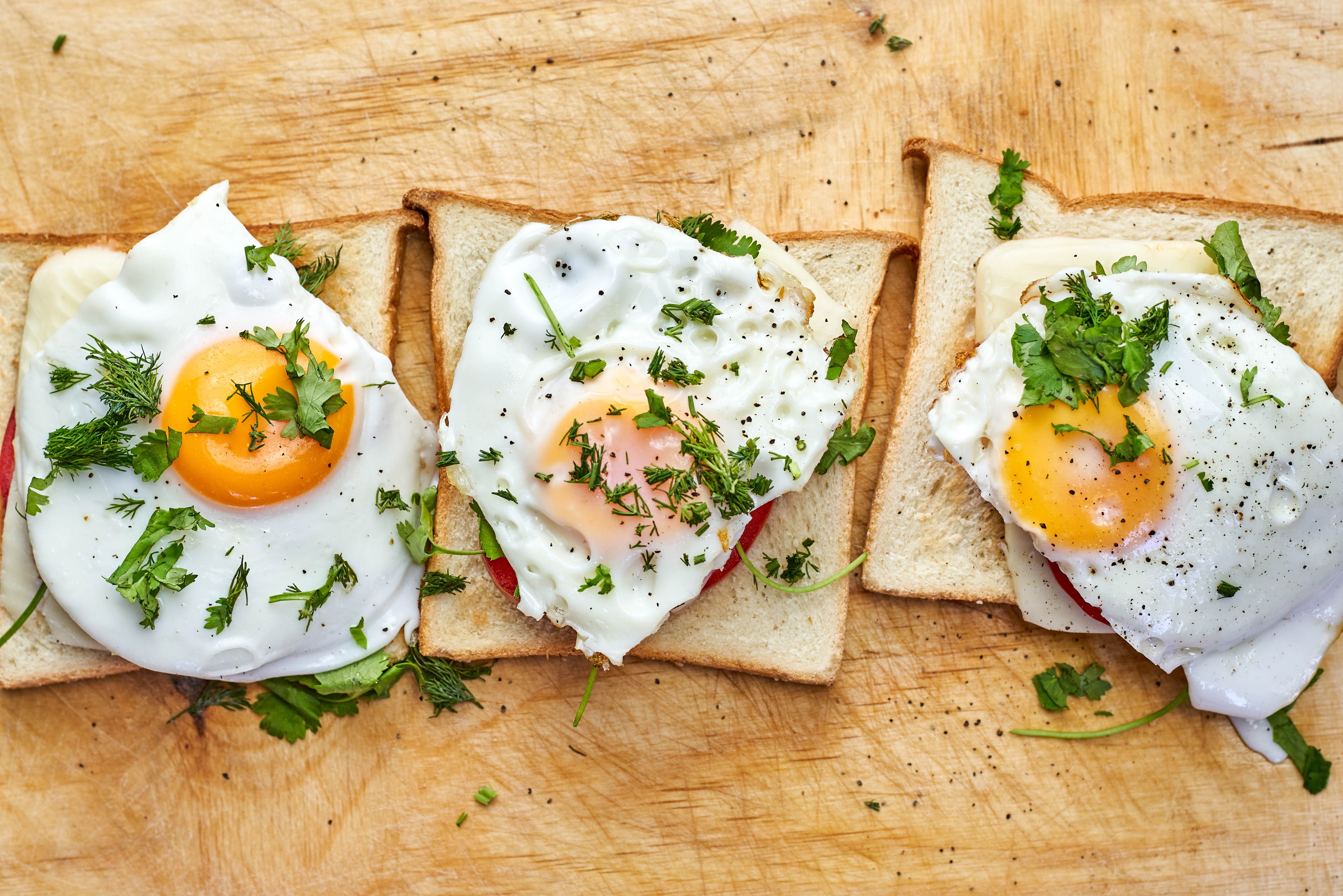 Three fried eggs on toast with herbs HD Wallpaper