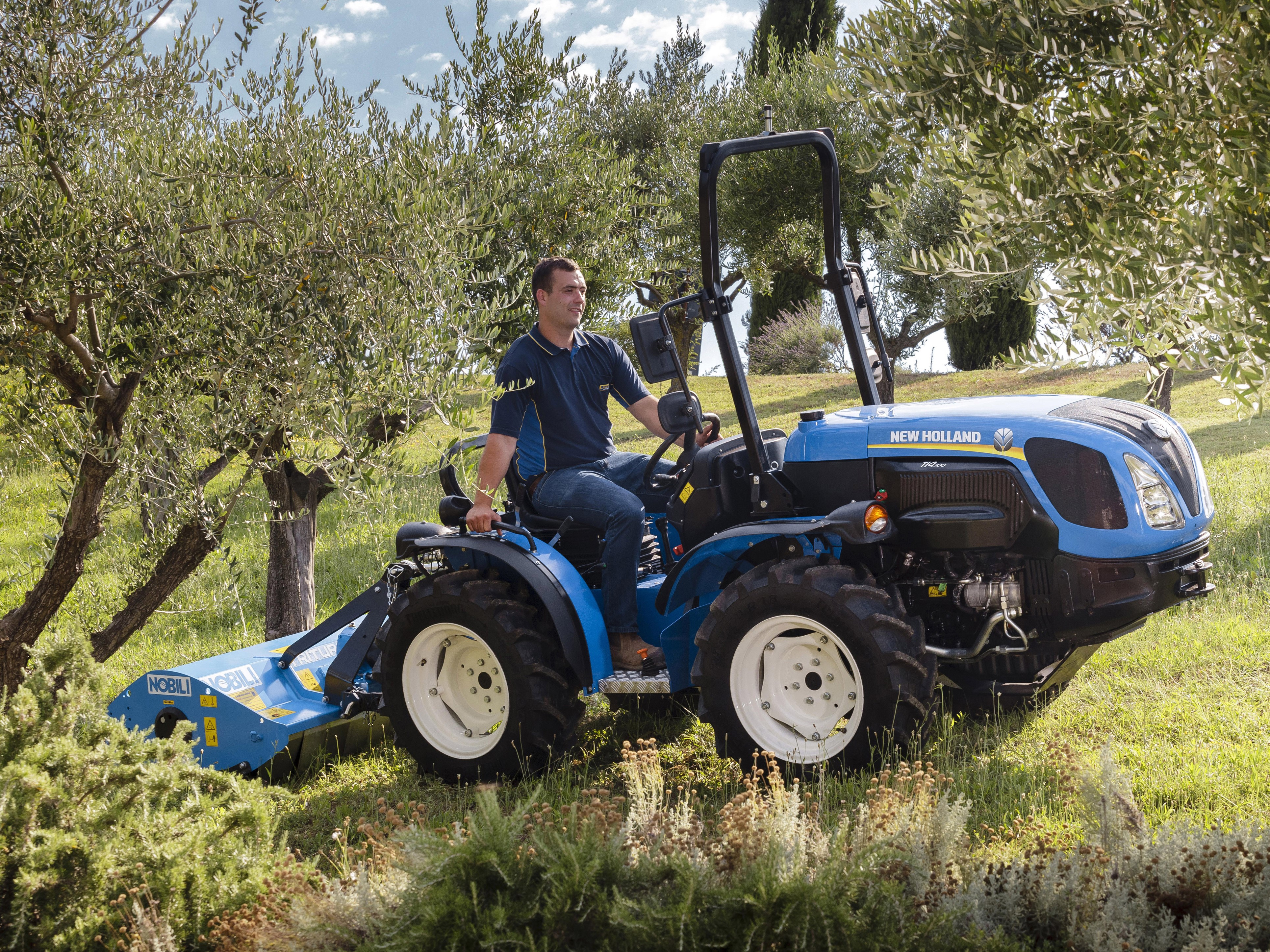 Man driving New Holland TI4.100 tractor with mower HD Wallpaper