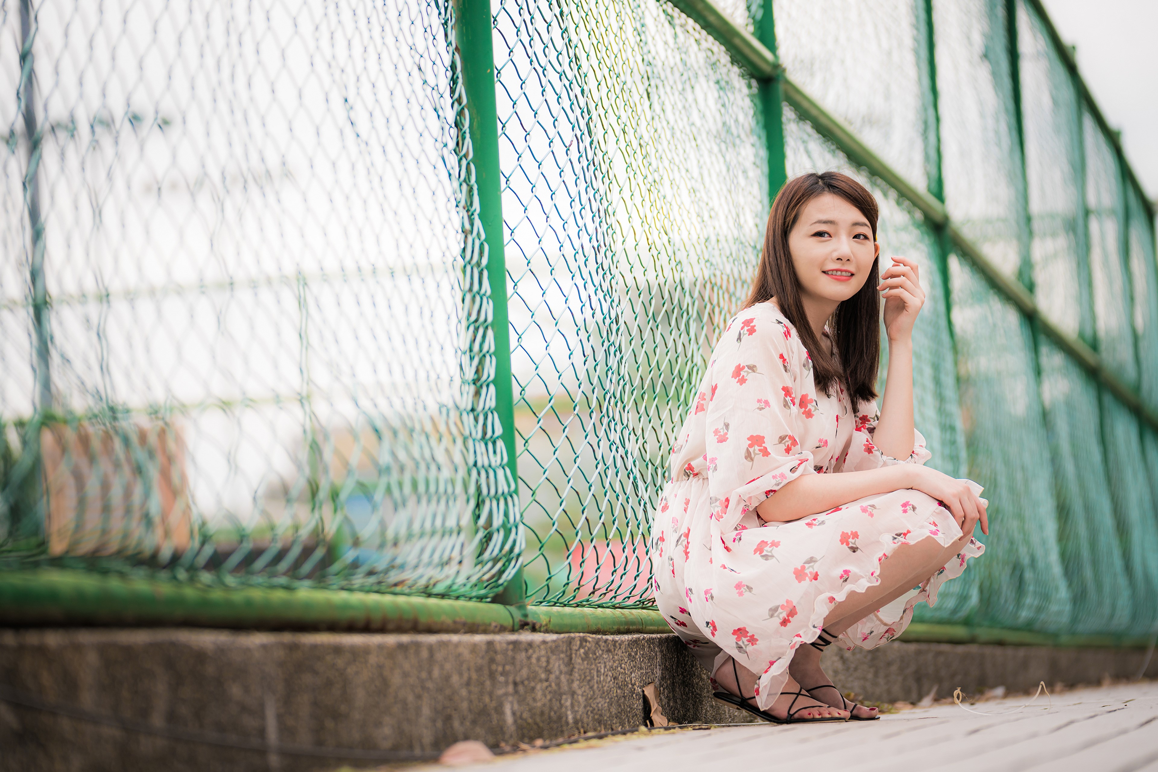 4K Asian Woman Sitting by Fence in Floral Dress HD Wallpaper