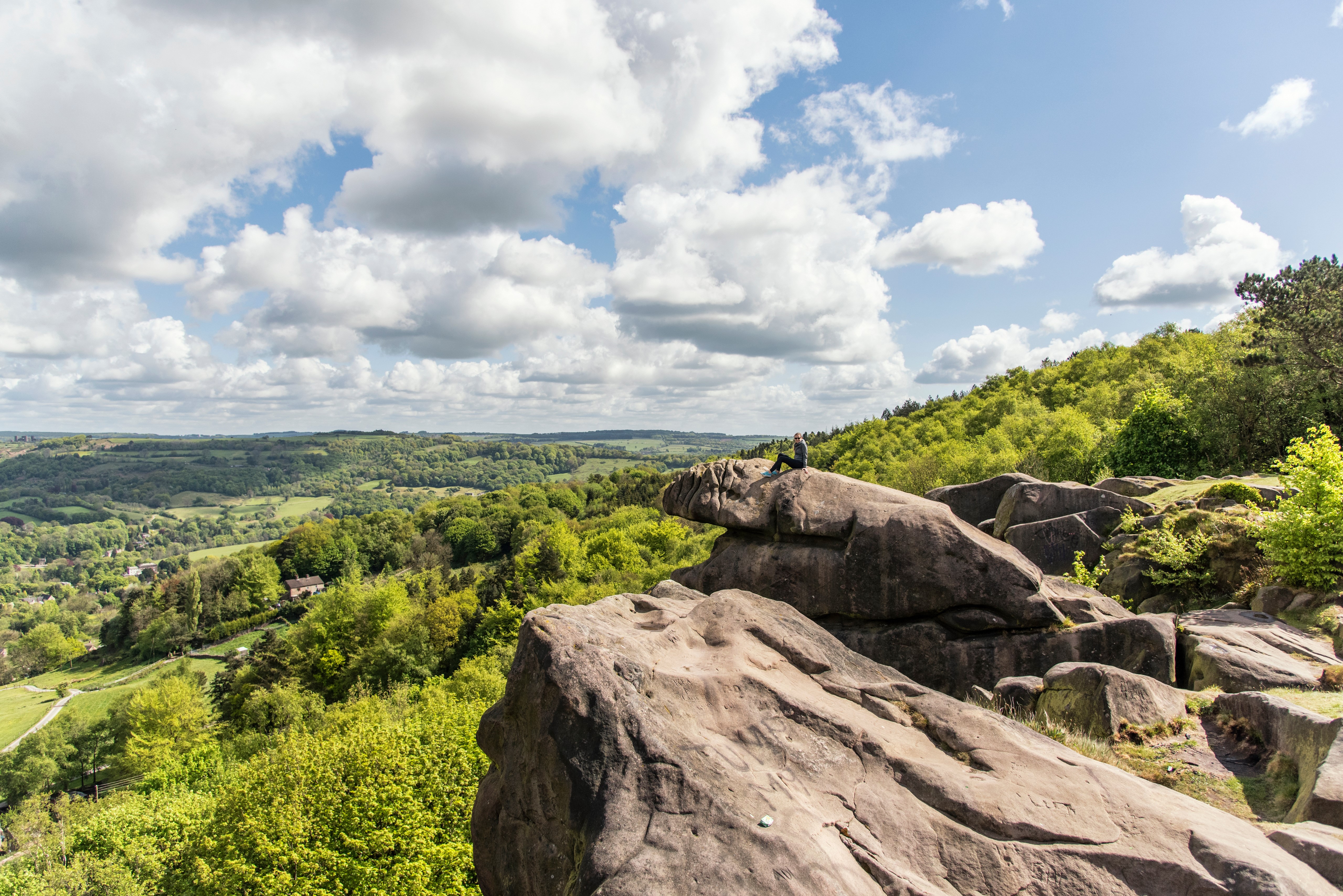 Person sitting on rocks overlooking Cromford, England HD Wallpaper