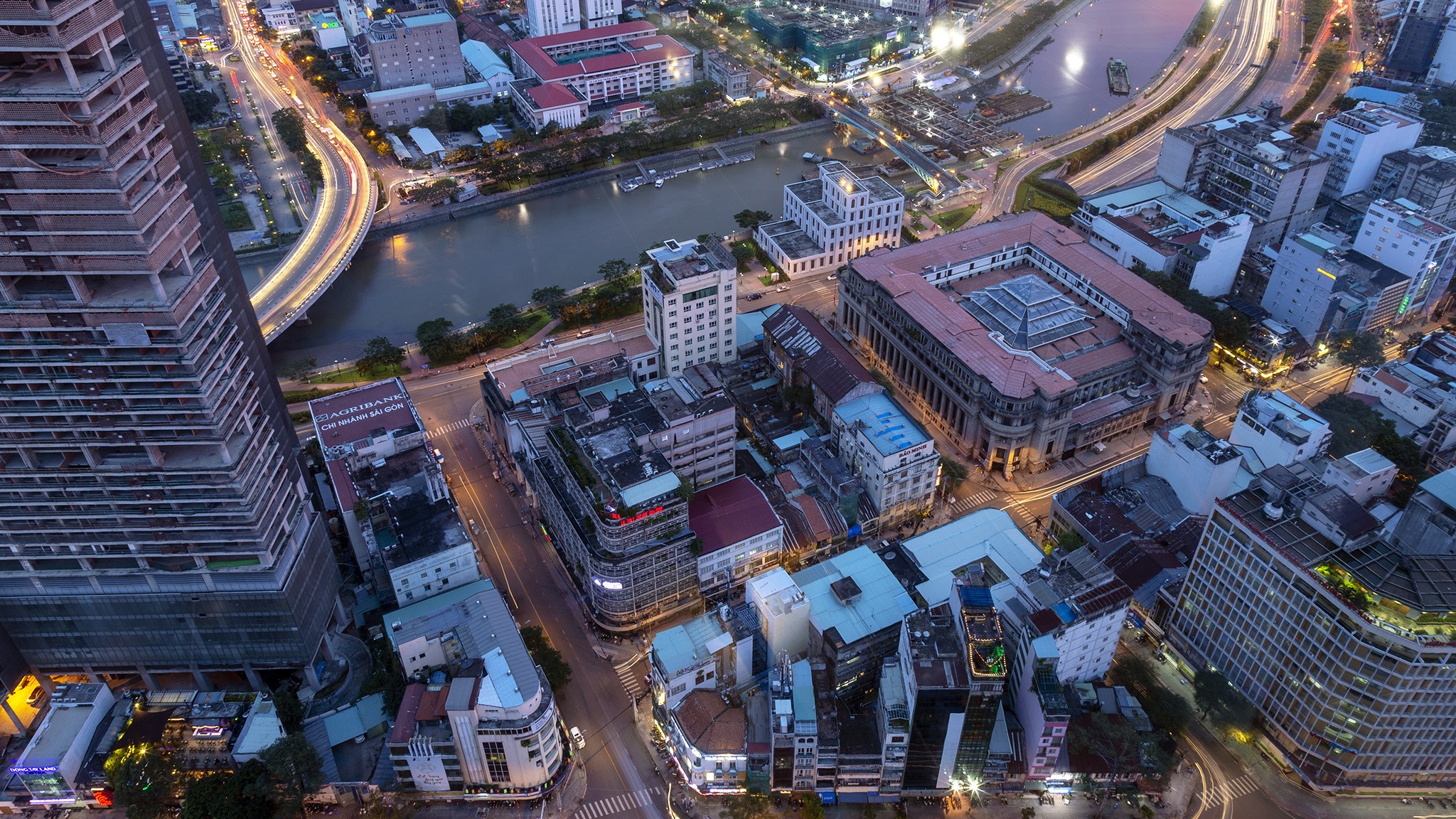 Aerial view of Saigon, Vietnam at dusk with river and buildings HD Wallpaper