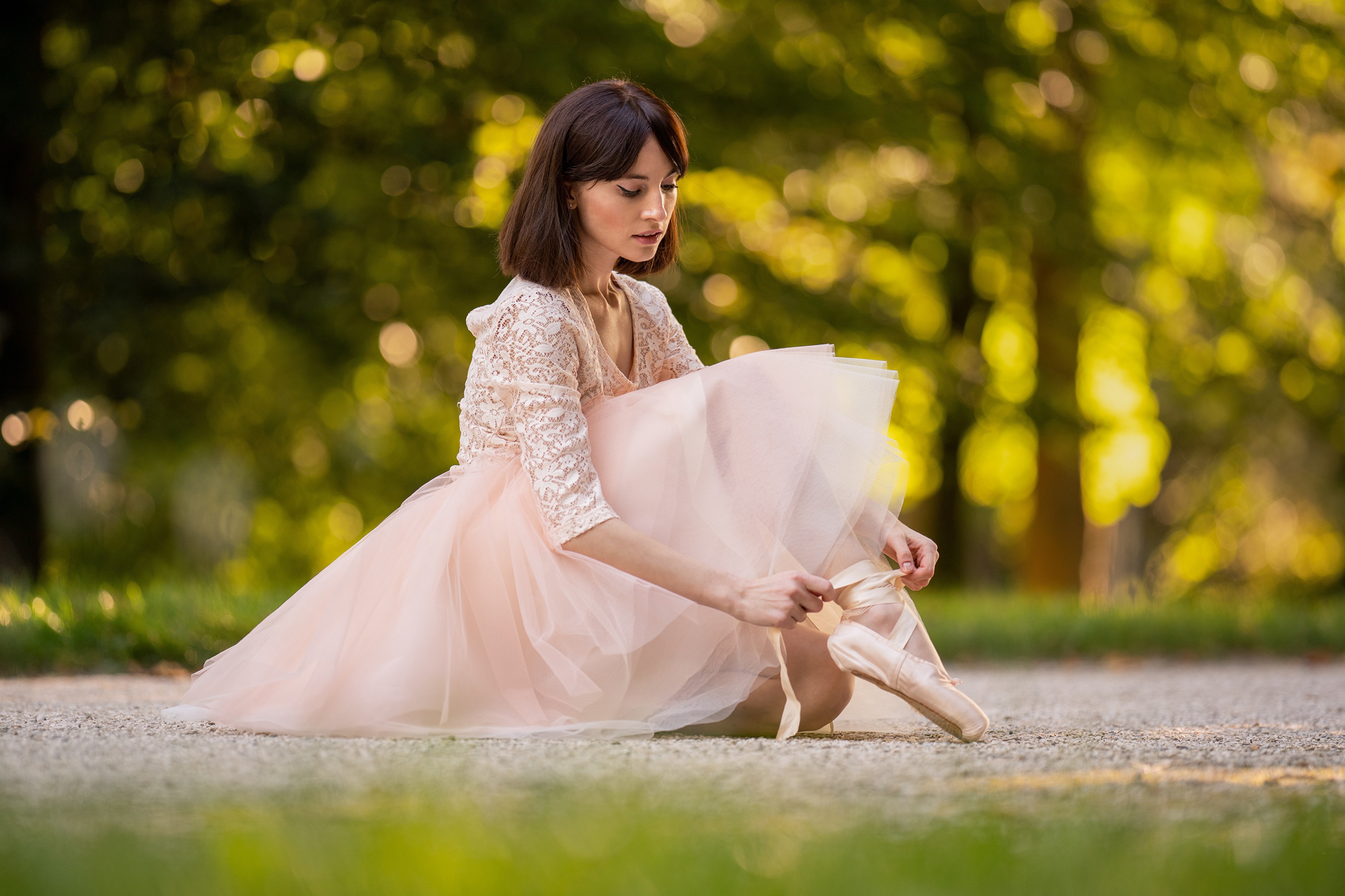 Ballerina tying pointe shoes in park HD Wallpaper