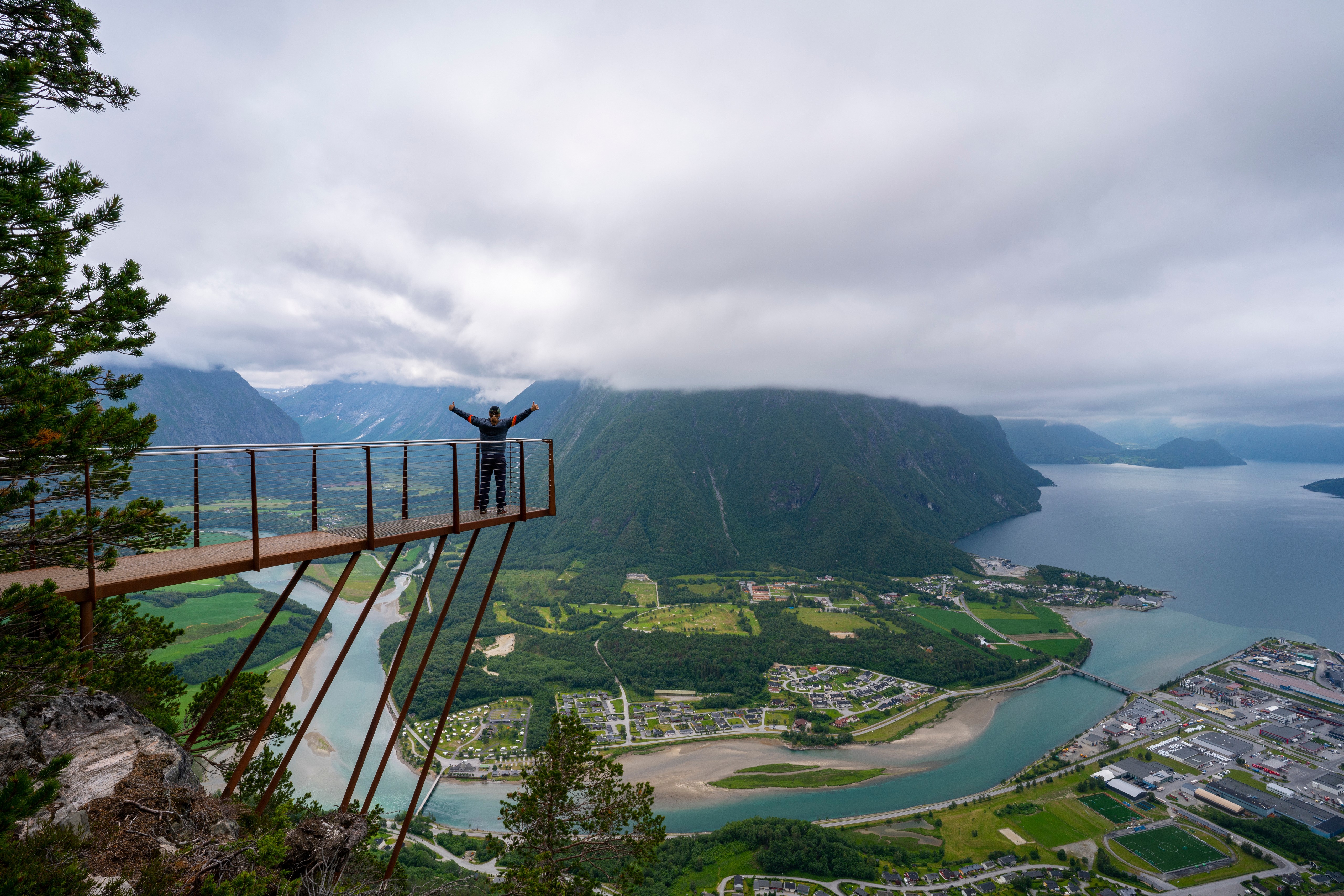 Person on viewpoint overlooking mountains and river in Norway HD Wallpaper