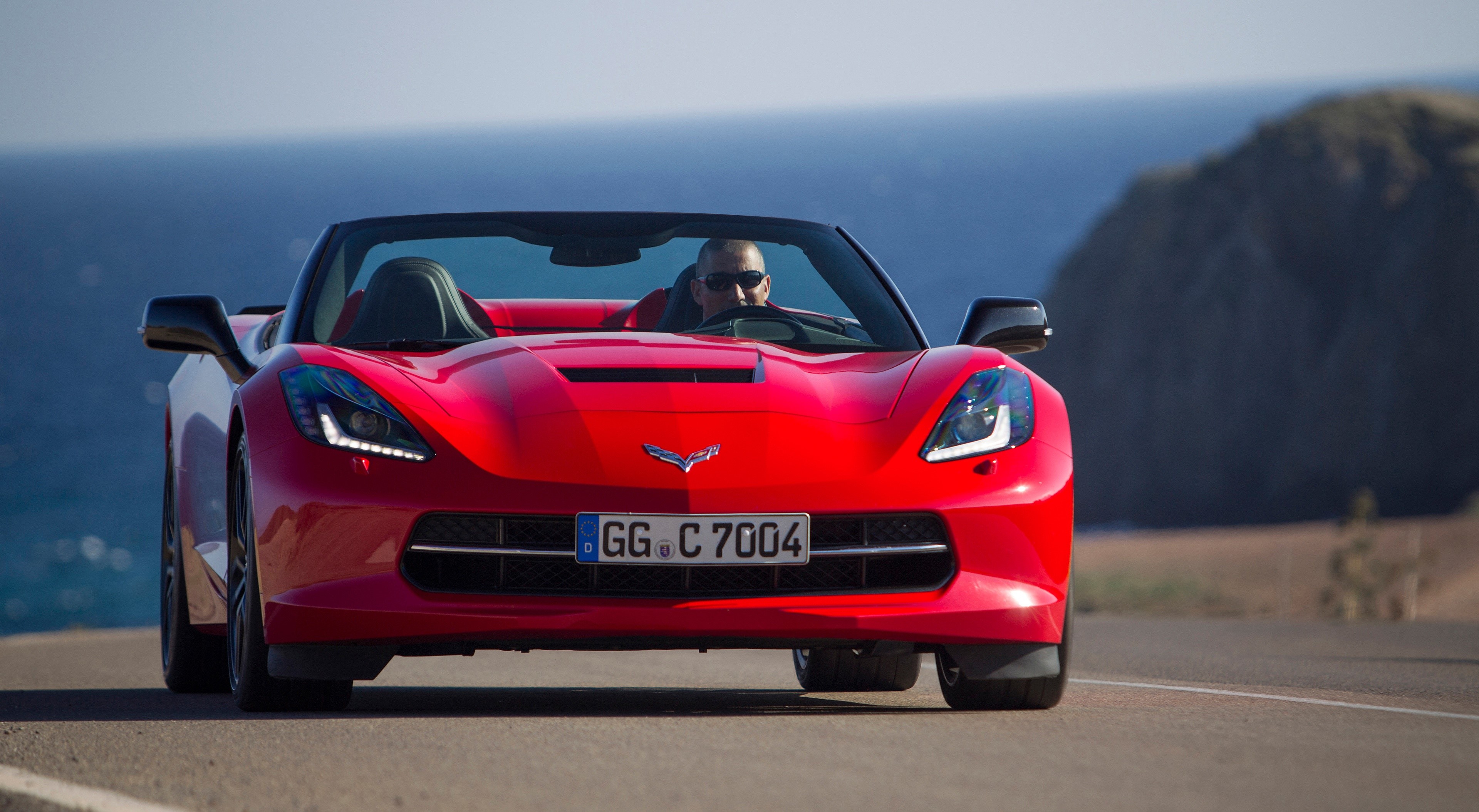 Red Chevrolet Corvette Stingray Convertible driving on a road HD Wallpaper