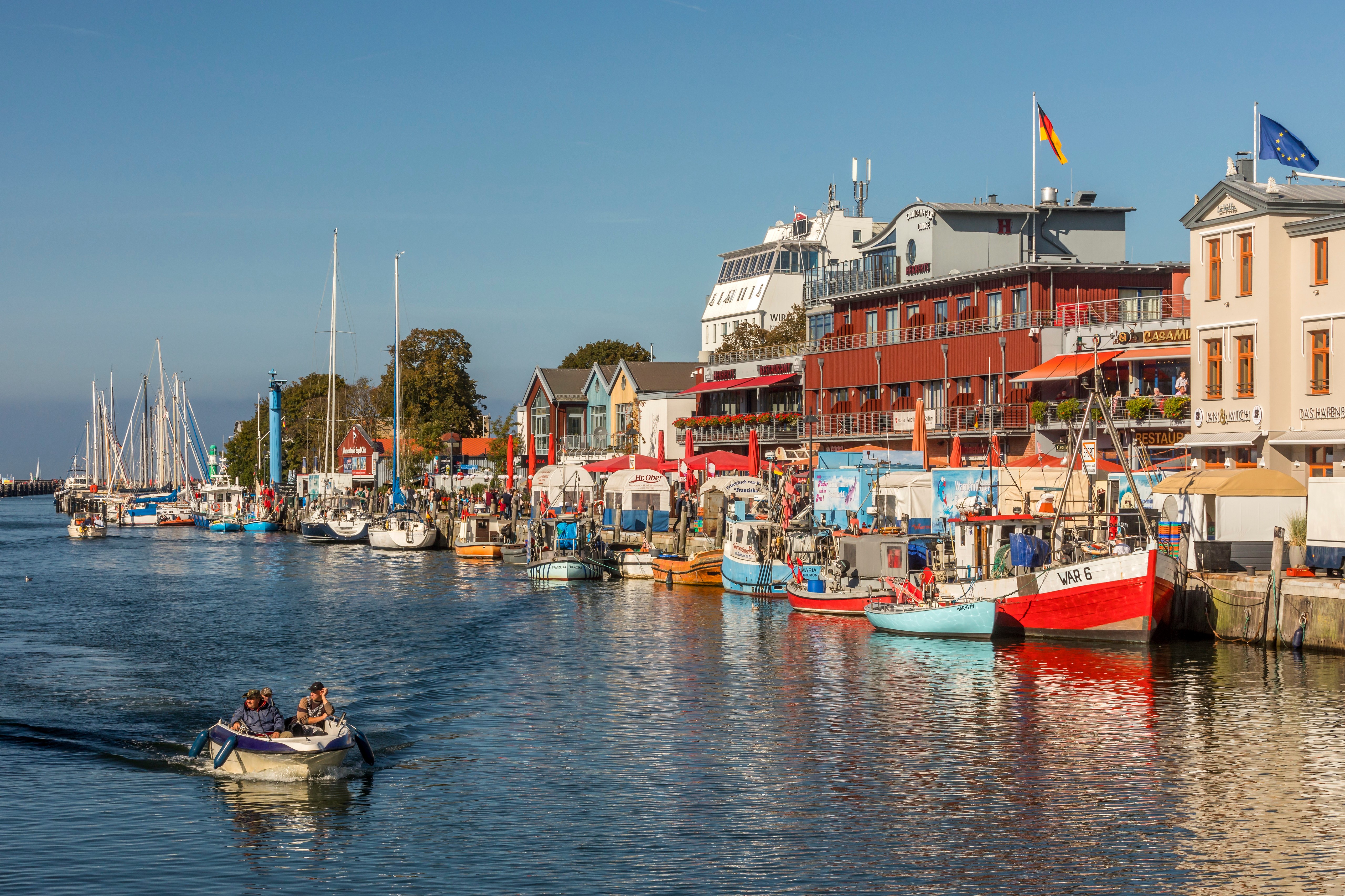 Boats docked at a German waterfront with houses and yachts HD Wallpaper