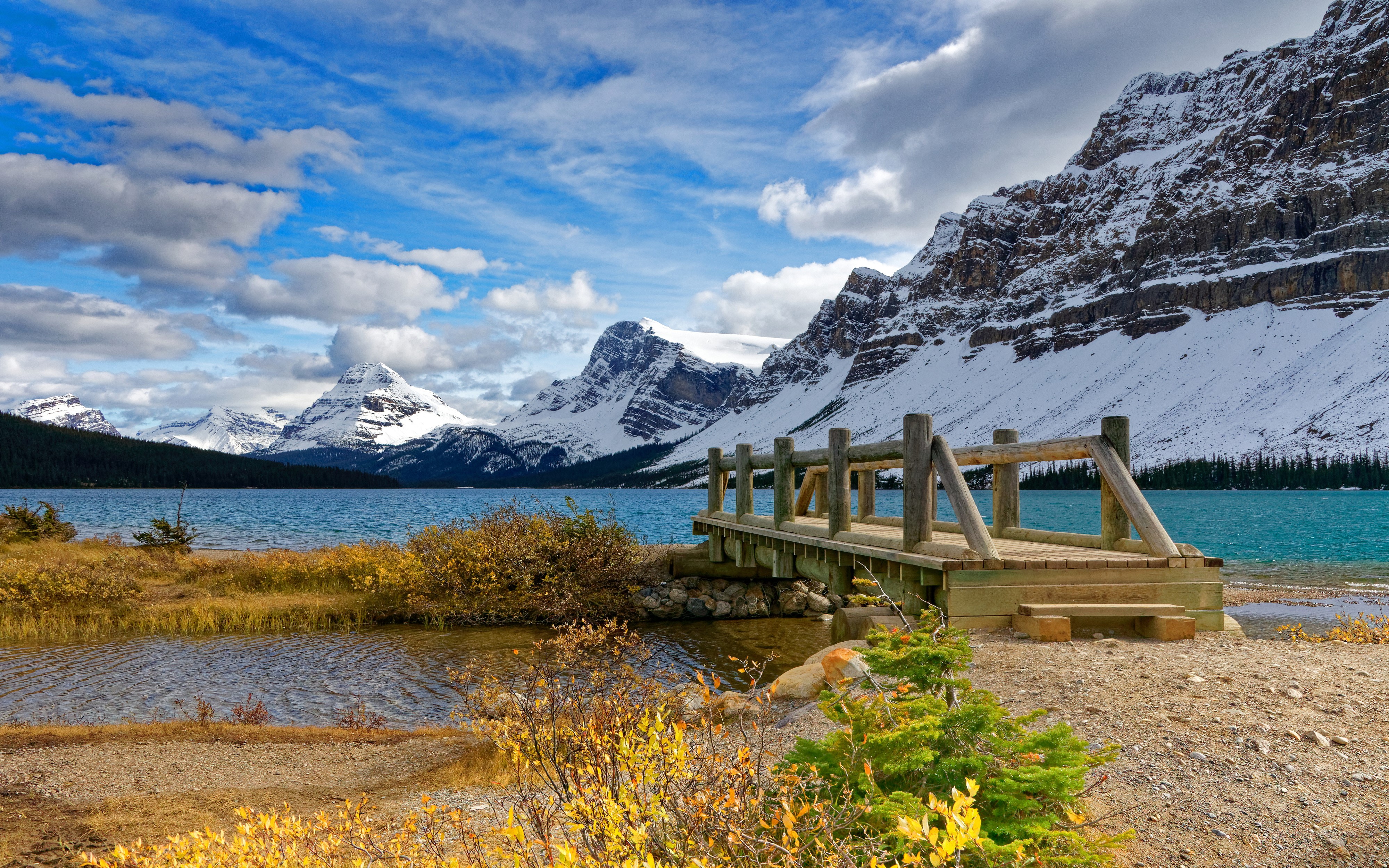 Wooden bridge over a lake with snow-capped mountains in Banff, Canada HD Wallpaper