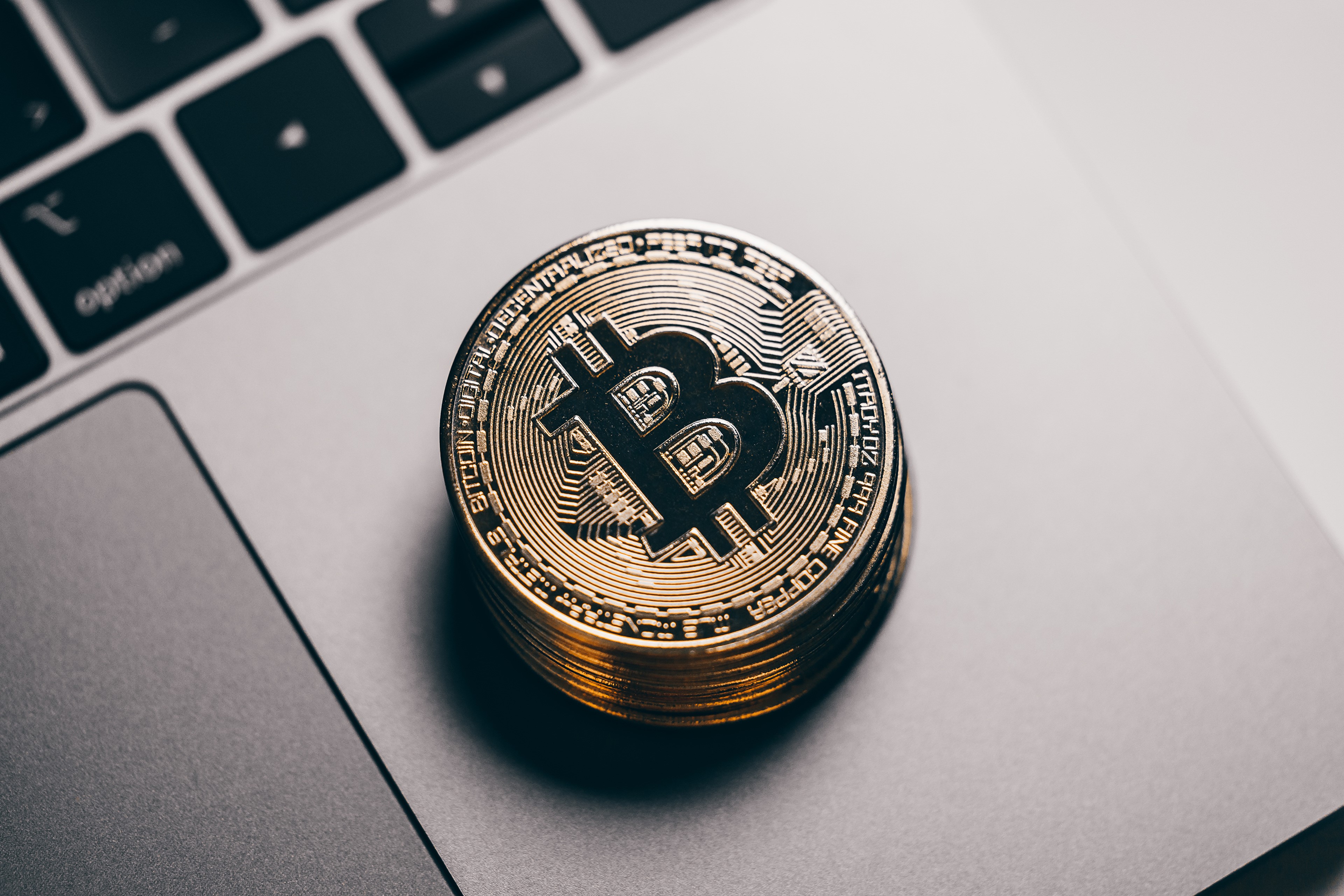 Stack of Bitcoin coins on a laptop keyboard HD Wallpaper