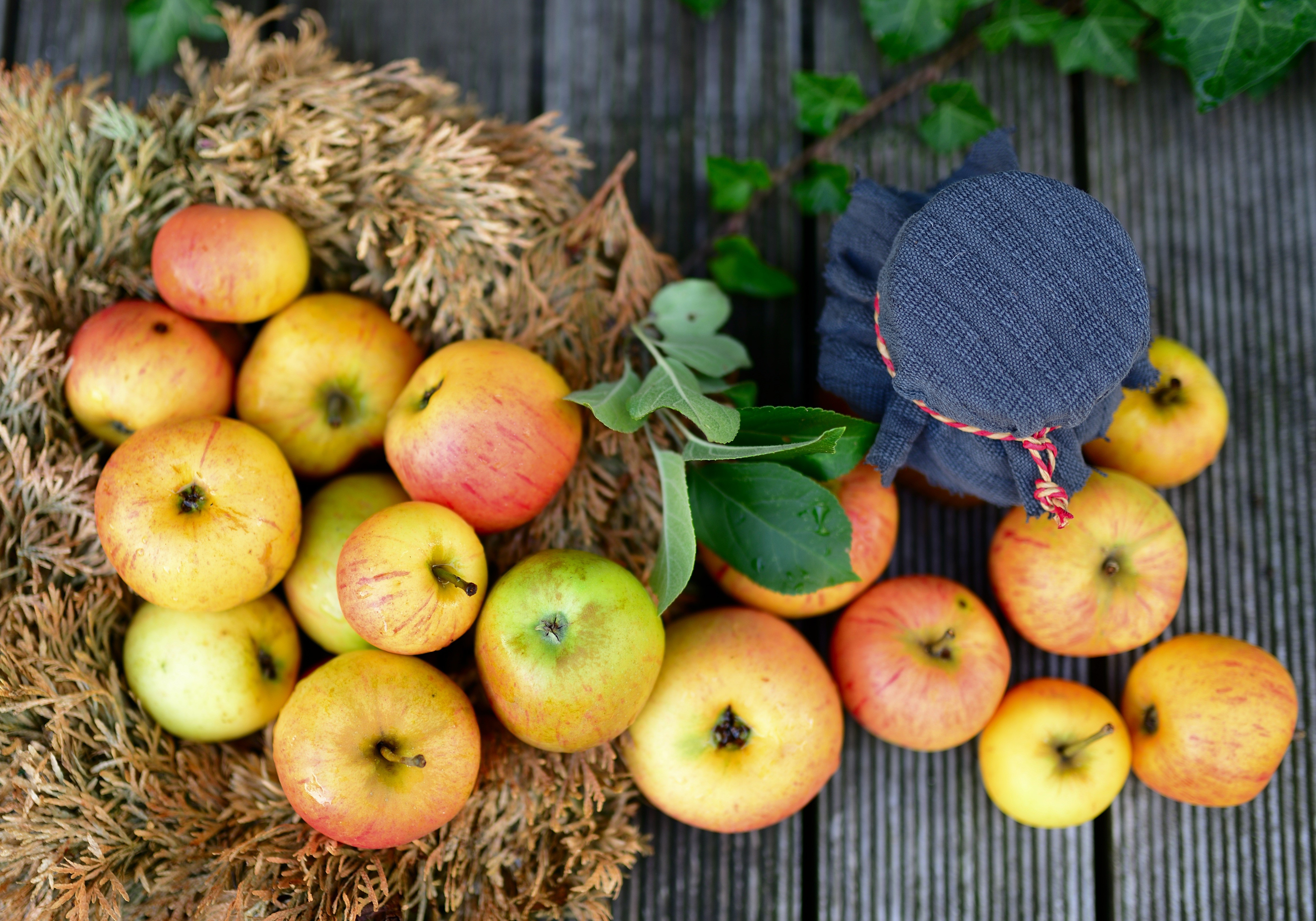 Apples on a wooden surface with foliage HD Wallpaper