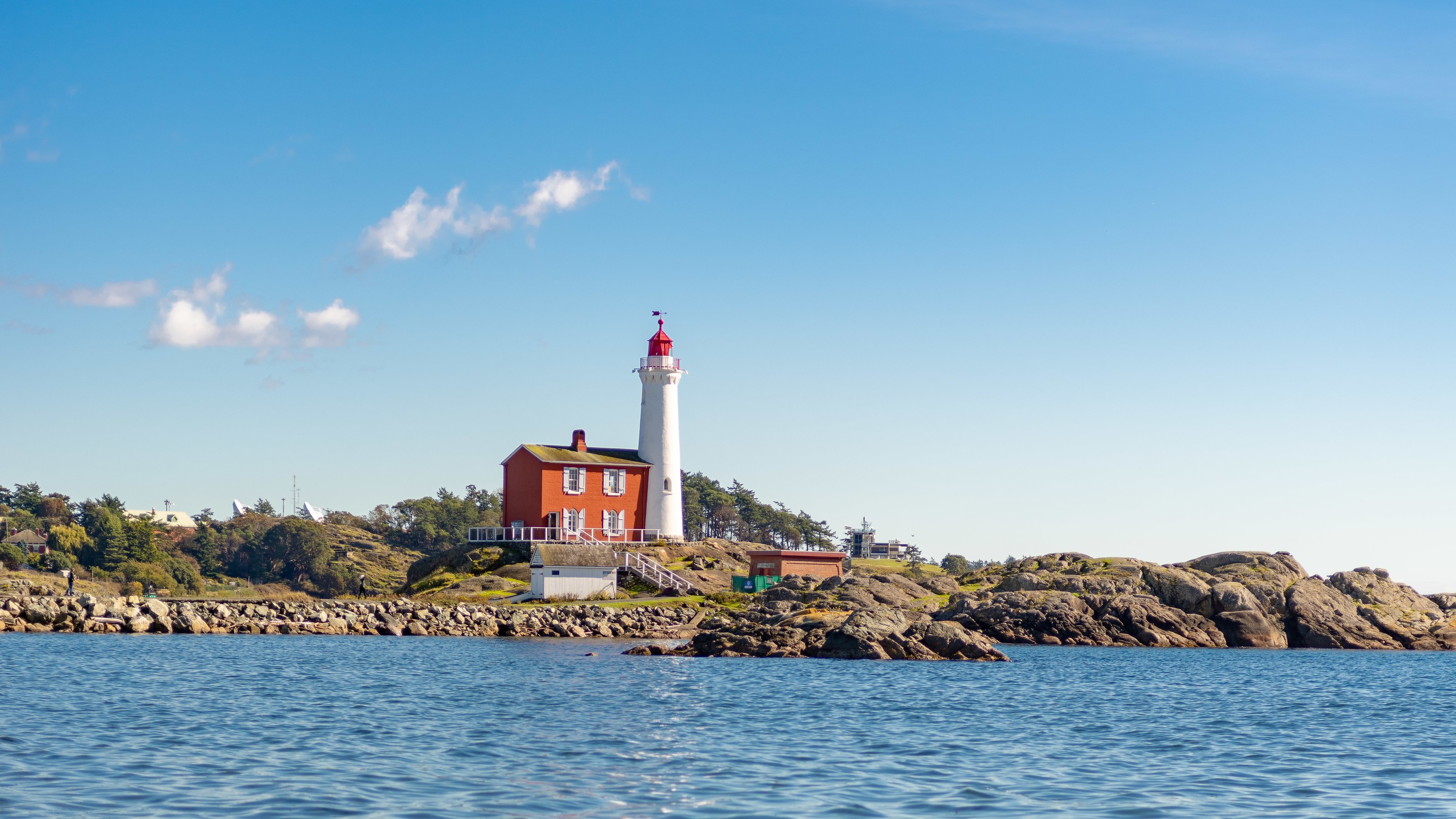 Fisgard Lighthouse on a rocky coast under a blue sky HD Wallpaper