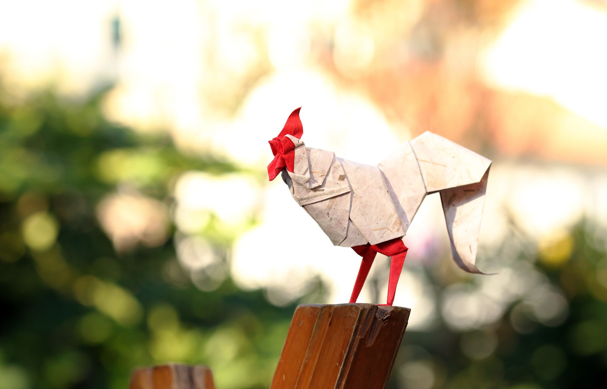 Origami rooster on a wooden perch with bokeh background HD Wallpaper