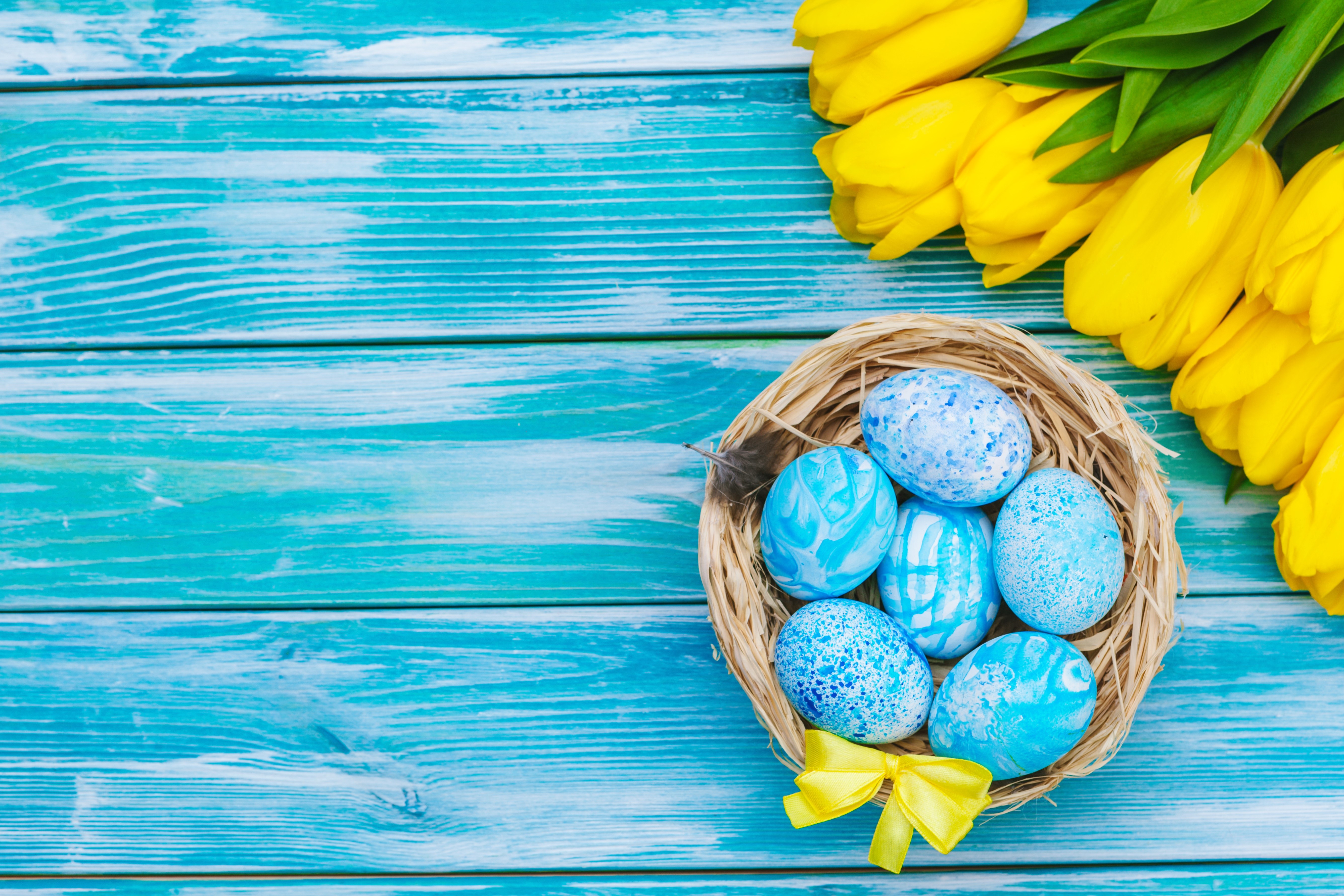 Easter eggs in a nest with yellow tulips on wood planks HD Wallpaper