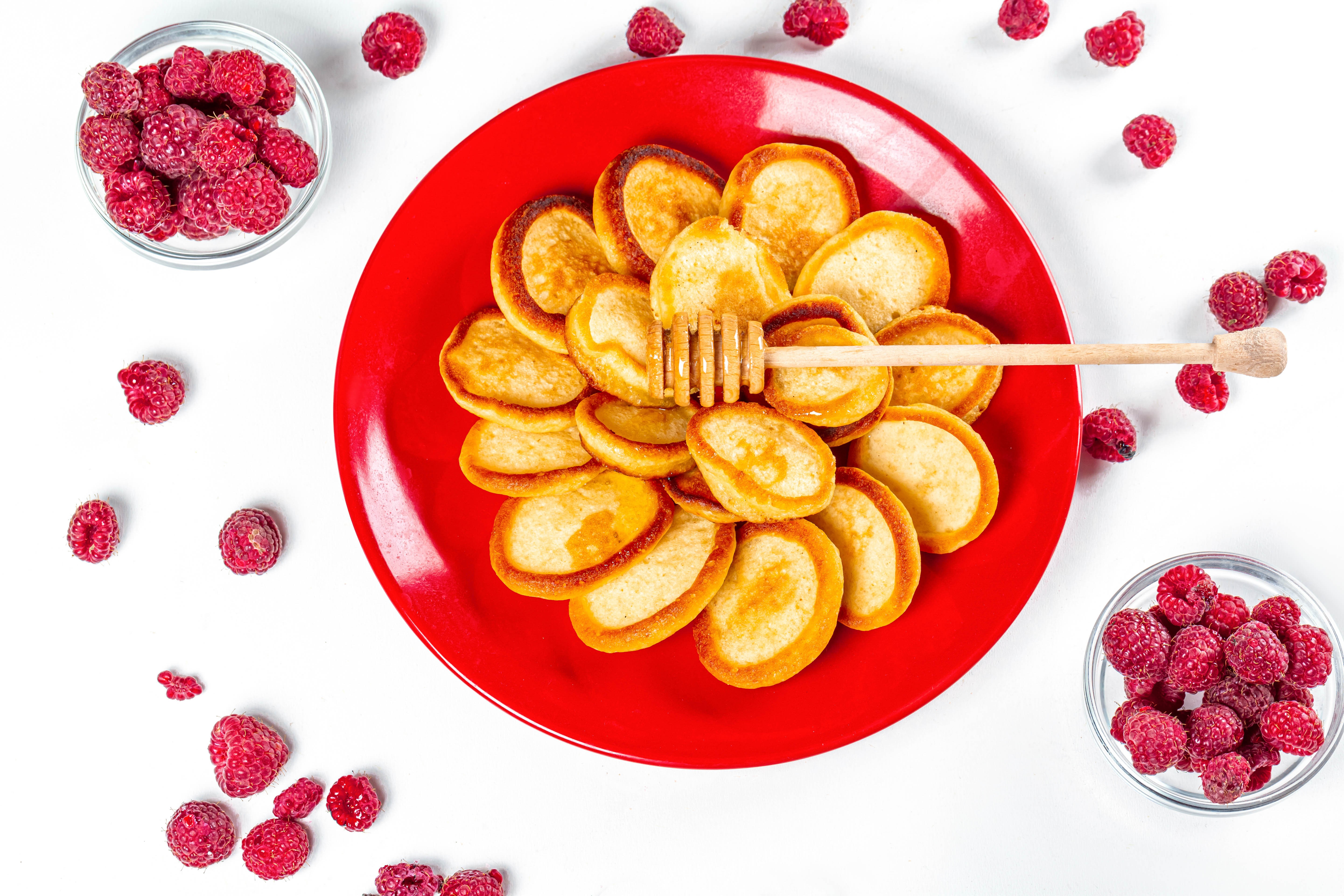 Mini pancakes with raspberries and honey on a red plate HD Wallpaper