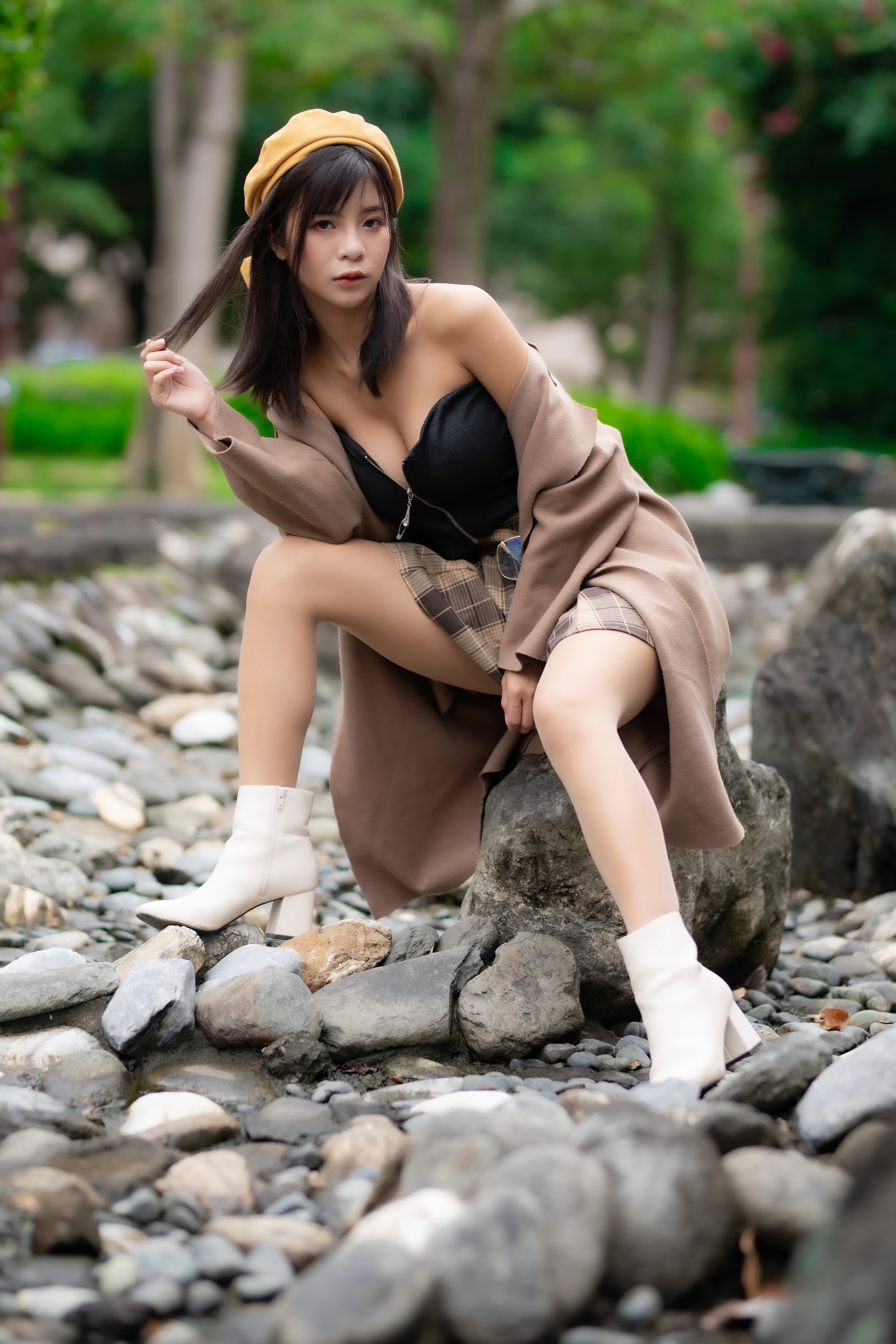 Asian woman wearing a beret and coat sitting on rocks HD Phone Wallpaper