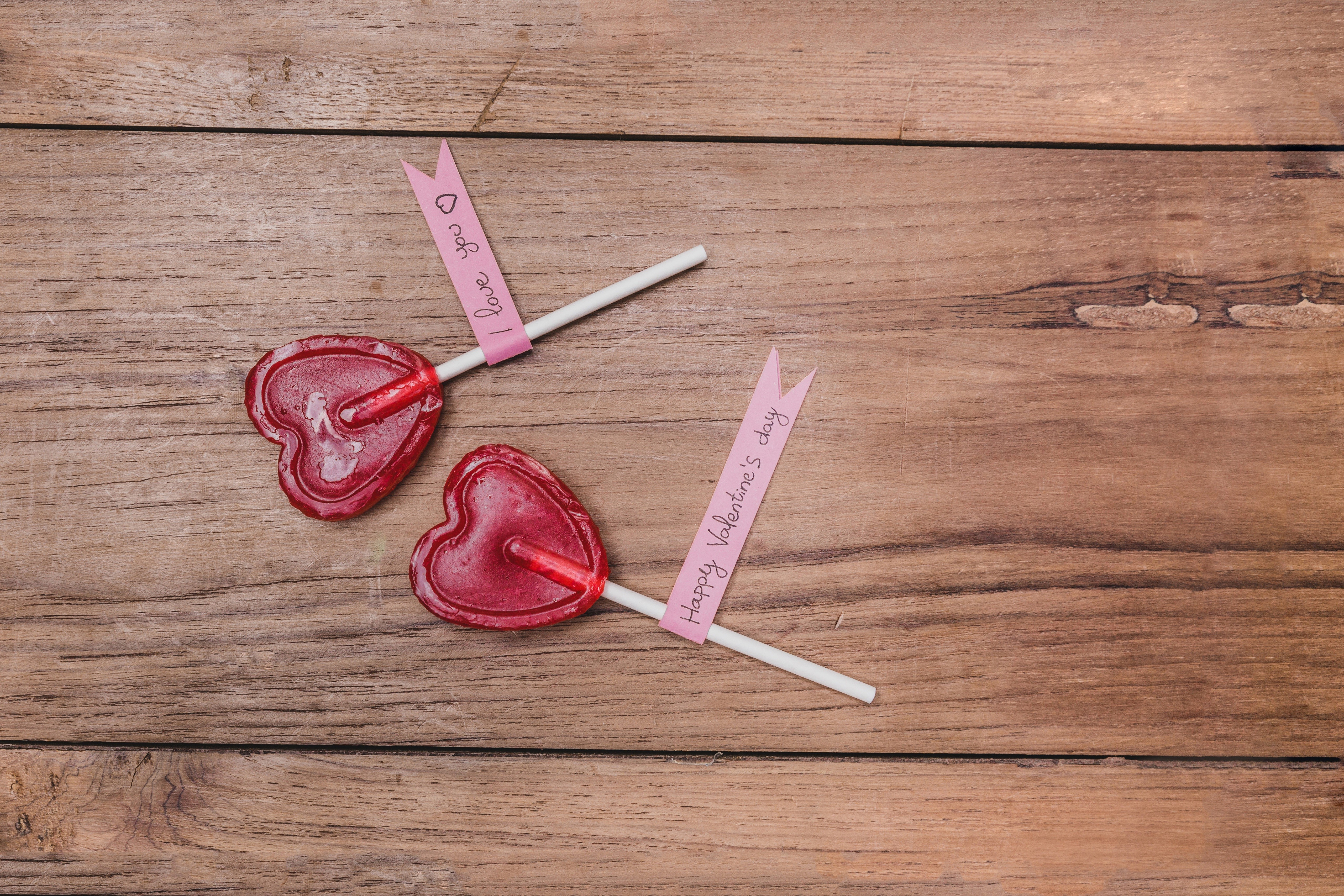 Two heart-shaped lollipops on wood planks HD Wallpaper
